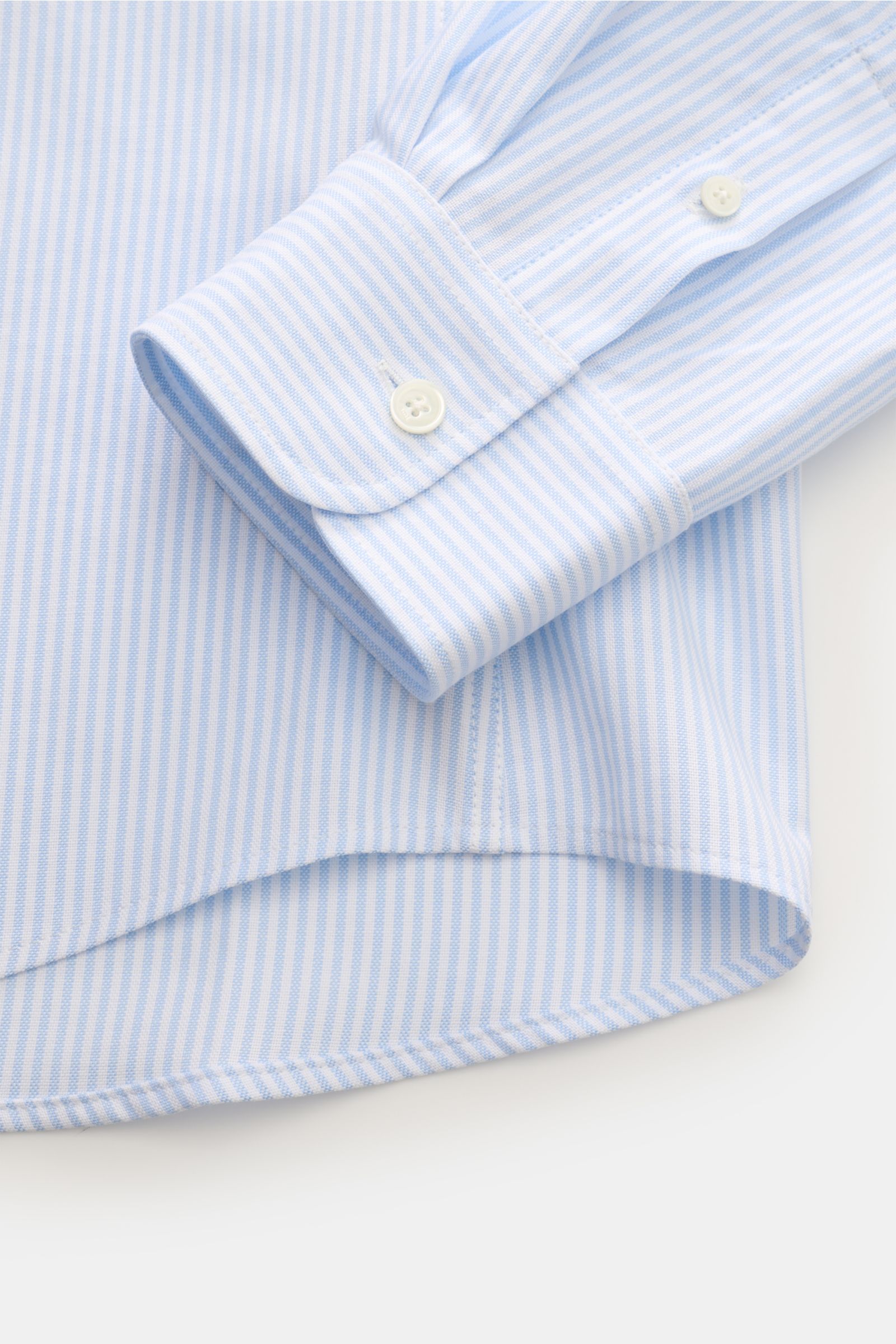 Nahaufnahme eines Ärmels und Saums von Ami Paris Oxford-Hemd Button-Down-Kragen hellblau/weiß gestreift, reine Baumwolle, Oversized Fit.