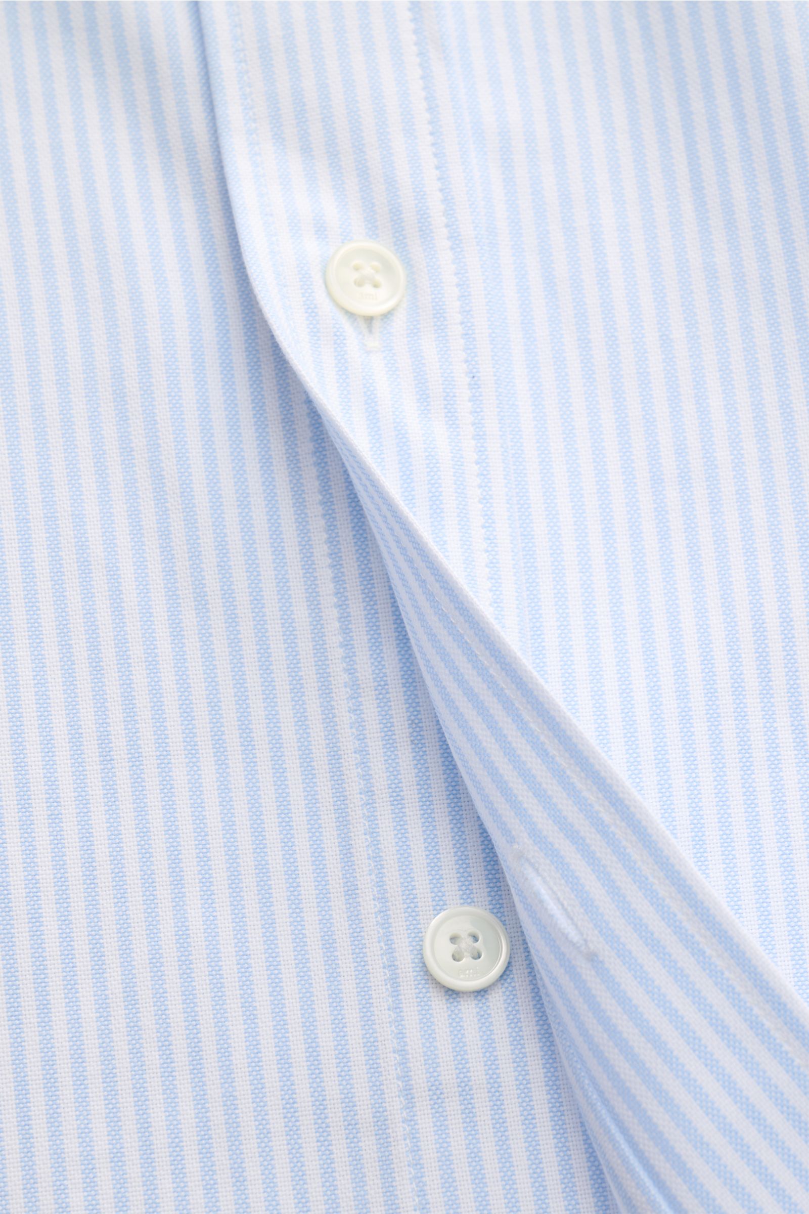 Nahaufnahme des sportlich-lässigen Ami Paris Oxford-Hemds Button-Down-Kragen hellblau/weiß gestreift mit feinem Streifenmuster, reiner Baumwolle, Oversized Fit und Knopfleiste.