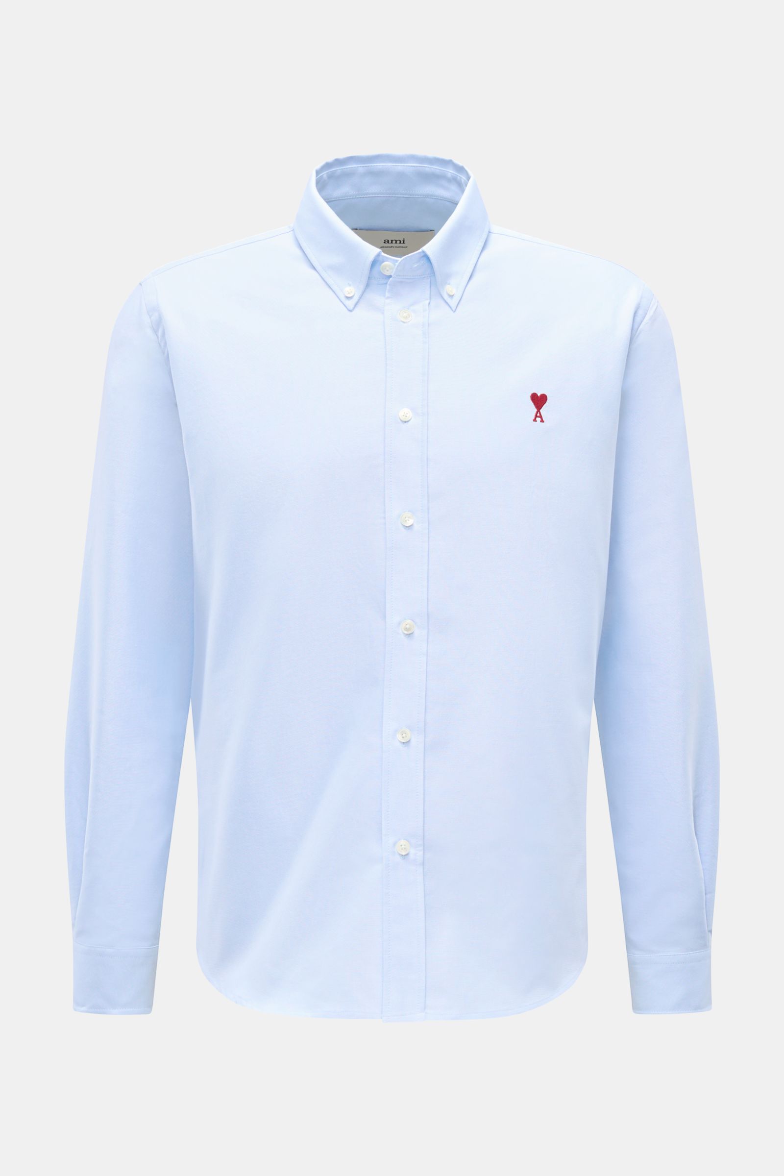 Front view of Ami Paris Oxford shirt button-down collar light blue, elegant with signature red heart stitching on chest, pure cotton Oxford fabric, regular fit, patch button placket with mother-of-pearl buttons, classic barrel cuffs, and rounded hem. 

