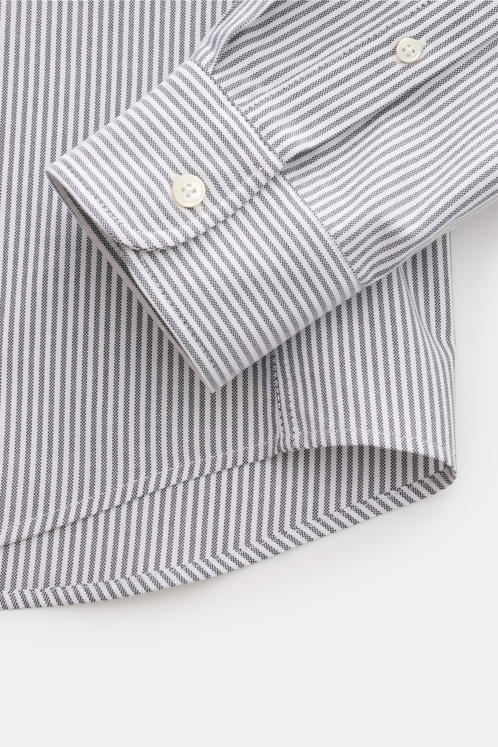 Nahaufnahme des Ami Paris Casual Hemd Button-Down-Kragen schwarz/weiß gestreift mit Oversized Fit, klassischer Sportmanschette und leicht gerundetem Saumverlauf, fotografiert von oben.