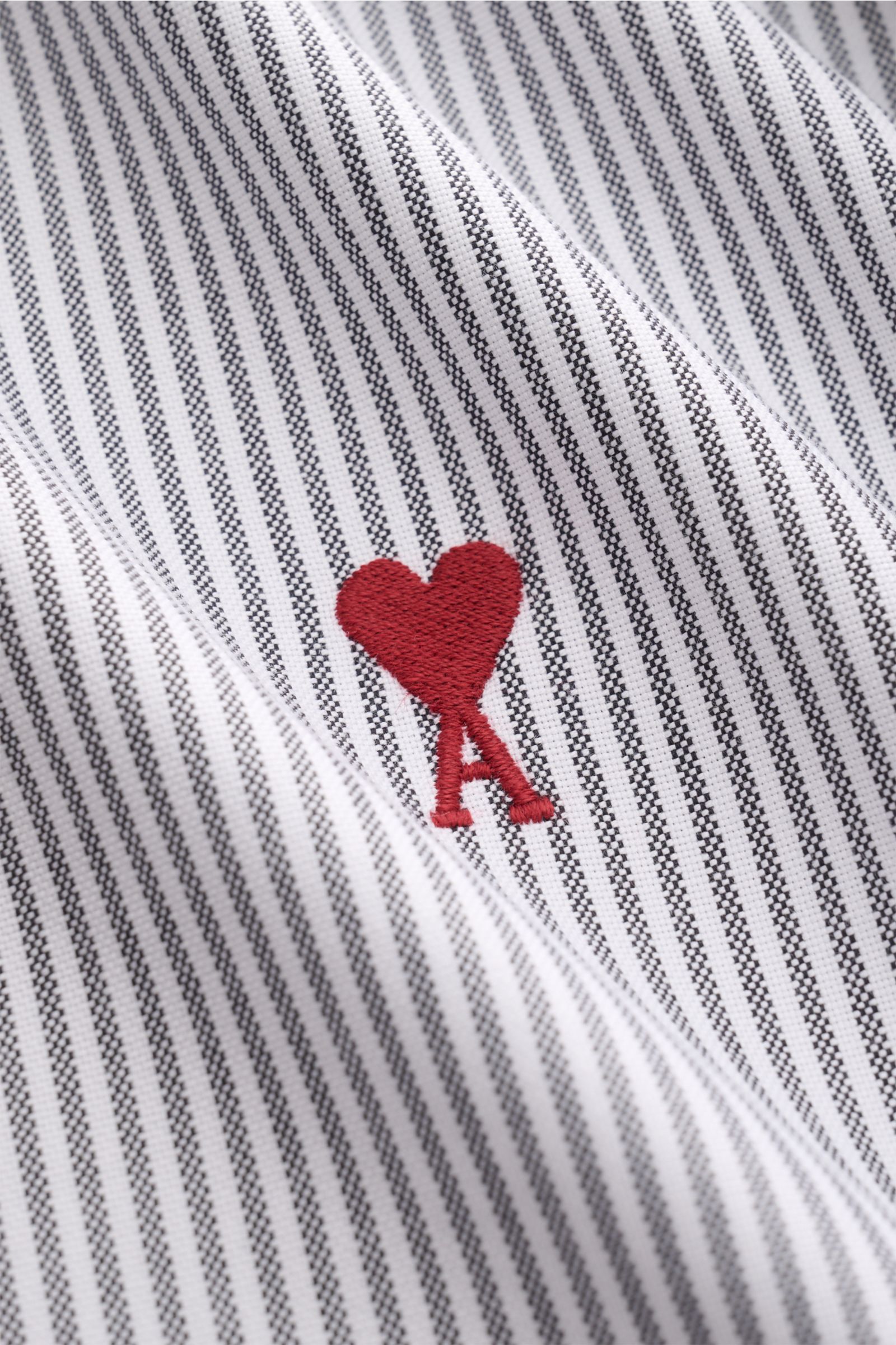 Ami Paris Casual Hemd Button-Down-Kragen schwarz/weiß gestreift, Detailaufnahme des klassischen Streifen-Designs mit rotem Herz-A-Logo, reine Baumwolle, weicher Griff, Oversized Fit.