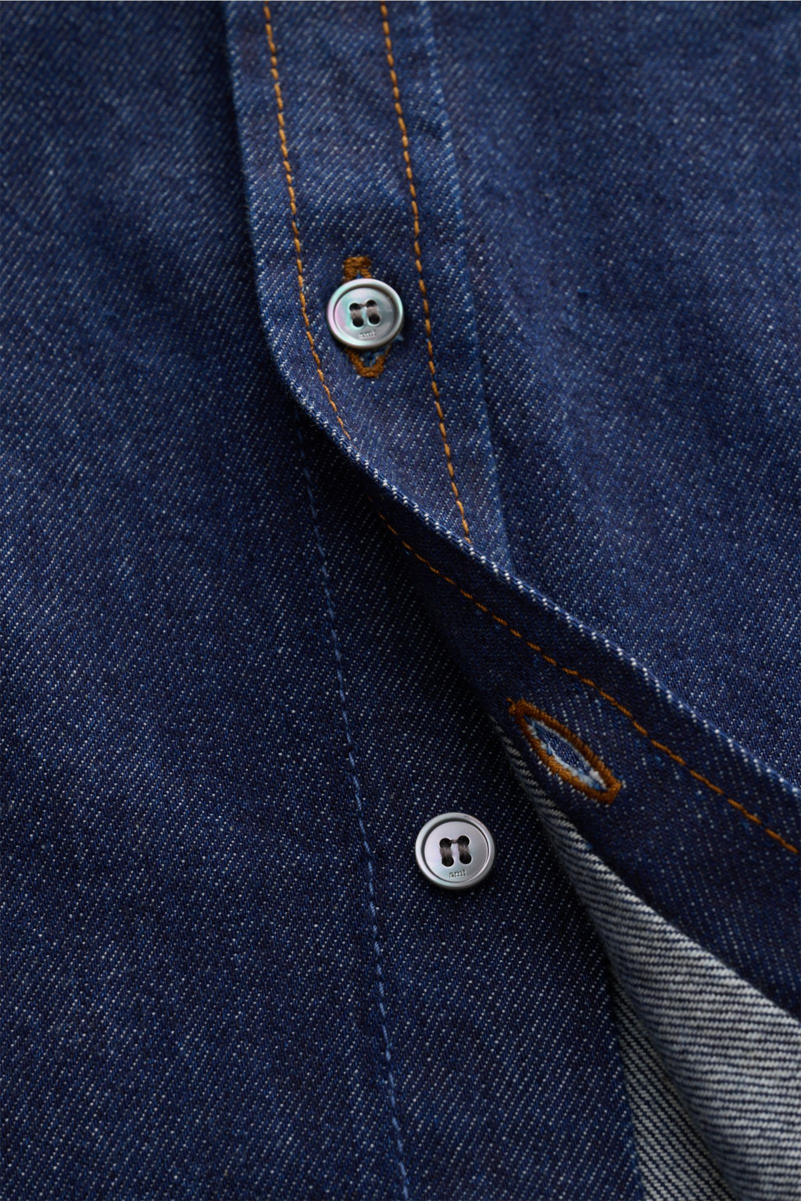 Nahaufnahme eines Ami Paris Jeanshemd Button-Down-Kragen navy aus reiner Baumwolle, oversized, mit Knöpfen, markentypischem Stick, Sportmanschette und gerundetem Saum.