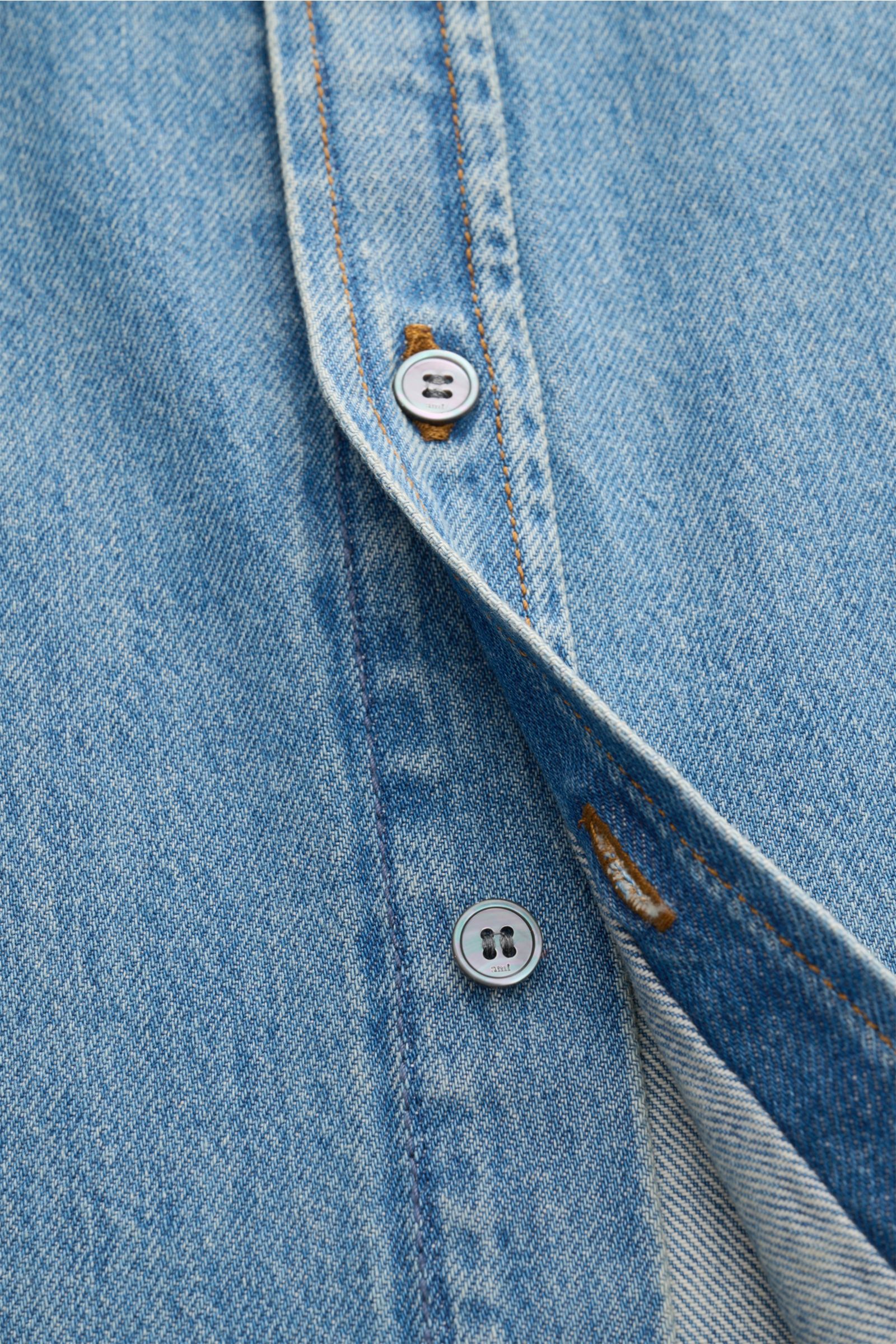 Nahaufnahme von Knöpfen und Naht am Ami Paris Jeanshemd Button-Down-Kragen rauchblau aus reiner Baumwolle mit leichter Struktur, Regular Fit, klassischer Sportmanschette und Logo-Stickerei, fotografiert aus schräger Perspektive.