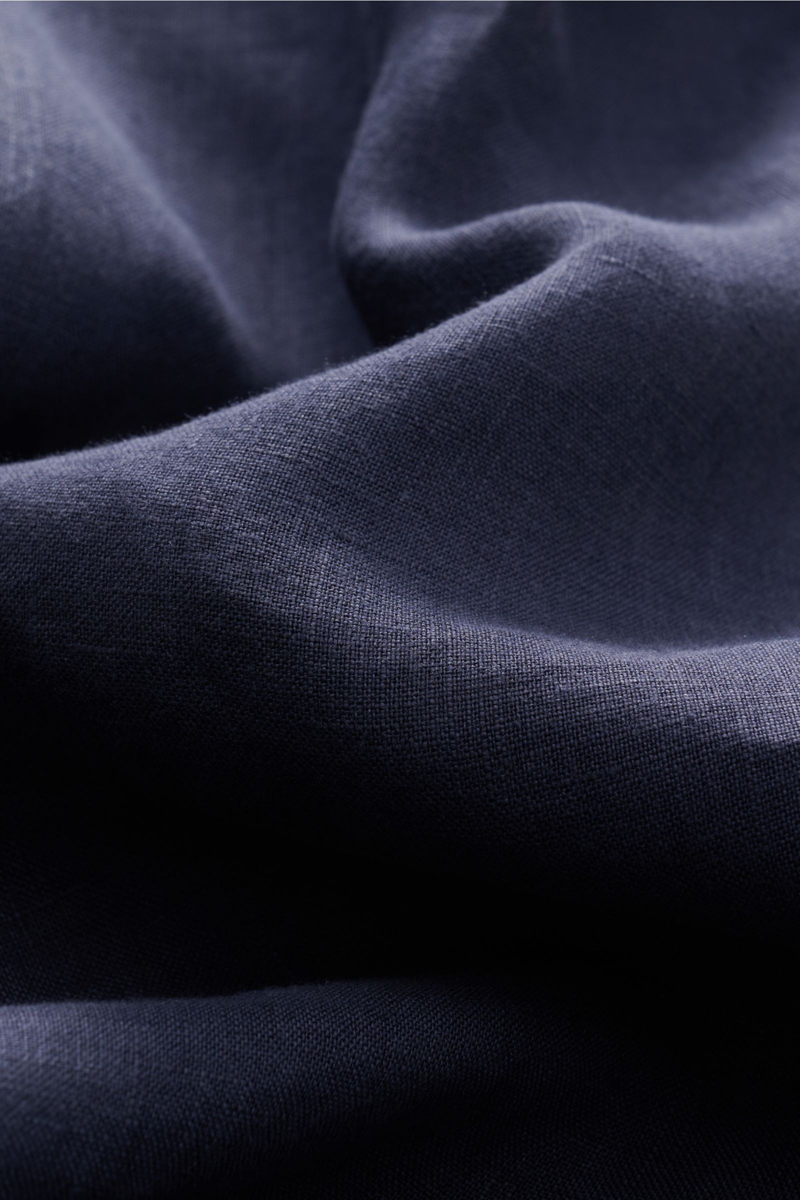Nahaufnahme eines navyfarbenen Stoffes mit feiner, strukturtypischer Leinenwebung, Detailaufnahme vom von Braun Leinenhemd Haifisch-Kragen navy, die textile Qualität zeigt mühelose Leichtigkeit und luftiges Tragegefühl.