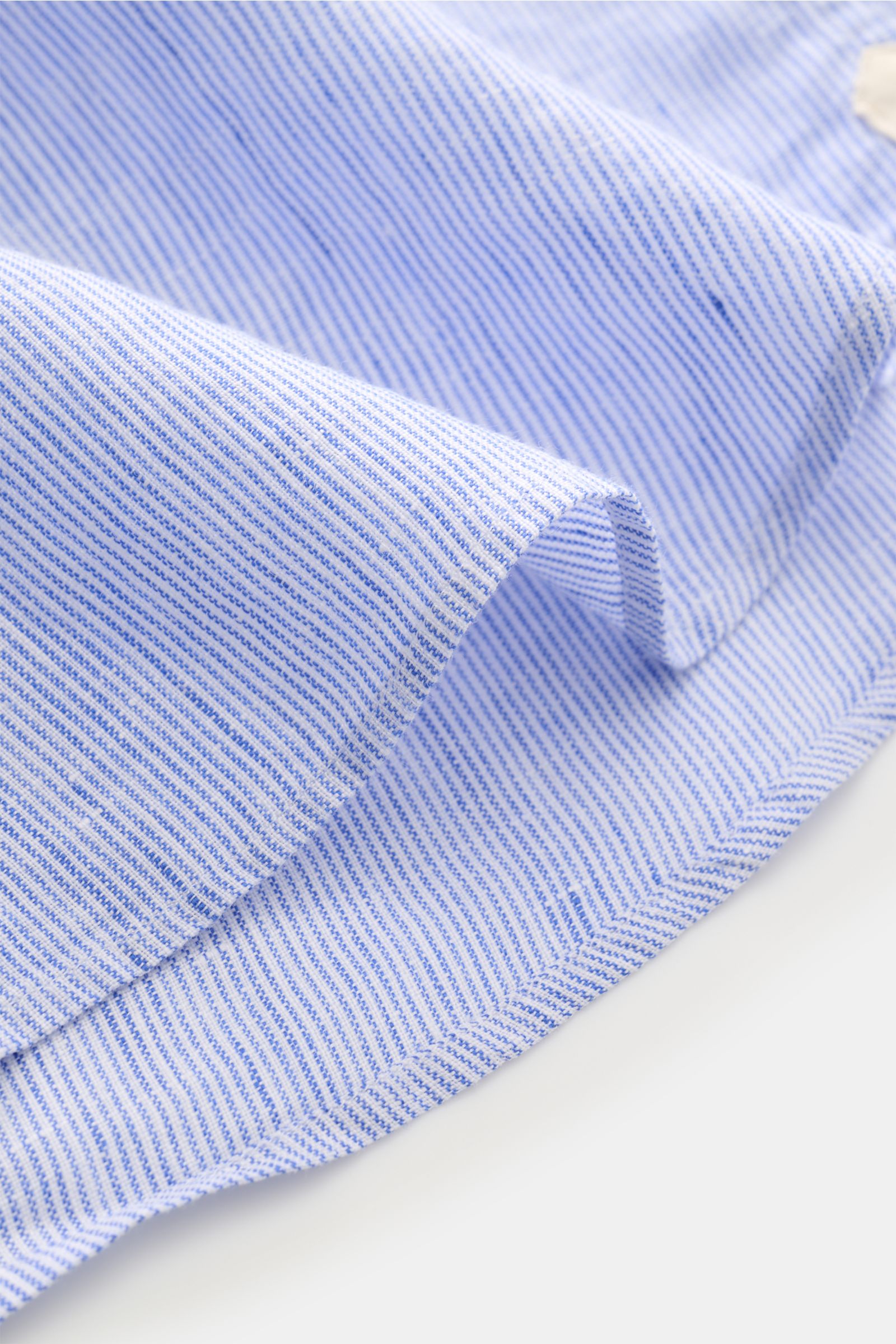 Close-up angled view of von Braun Linen shirt shark collar blue/white striped fabric showing fine stripes, airy pure linen texture, and rounded hem. Effortlessly lightweight: This VON BRAUN shirt in pure linen has an airy feel and a relaxed look – a styli