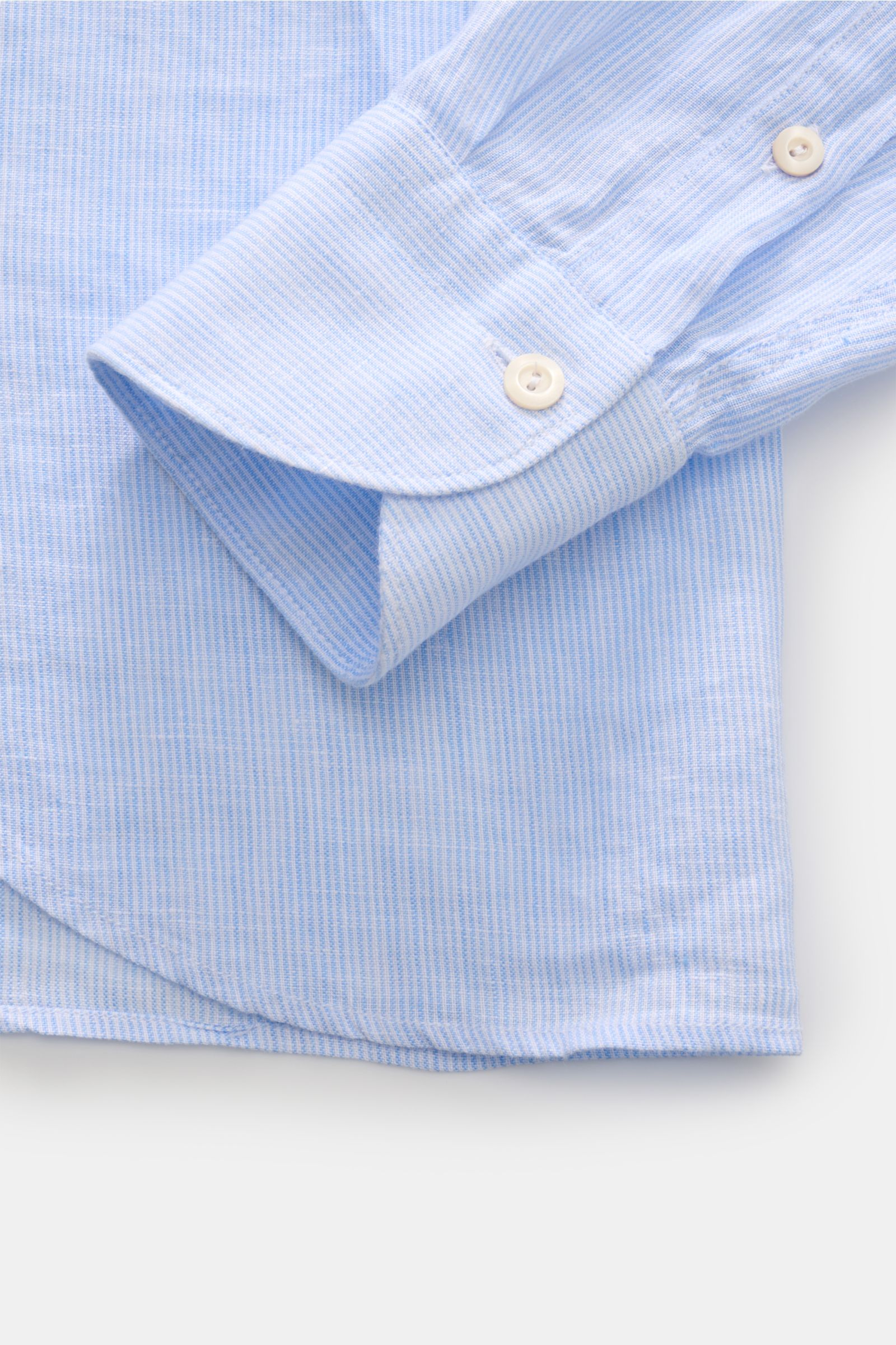 Nahaufnahme eines Manschettenbereichs des von Braun Leinenhemd Haifisch-Kragen hellblau/weiß gestreift aus reinem Leinen, mit feinem Streifenmuster, weichem Griff und klassischer Sportmanschette, fotografiert von oben.