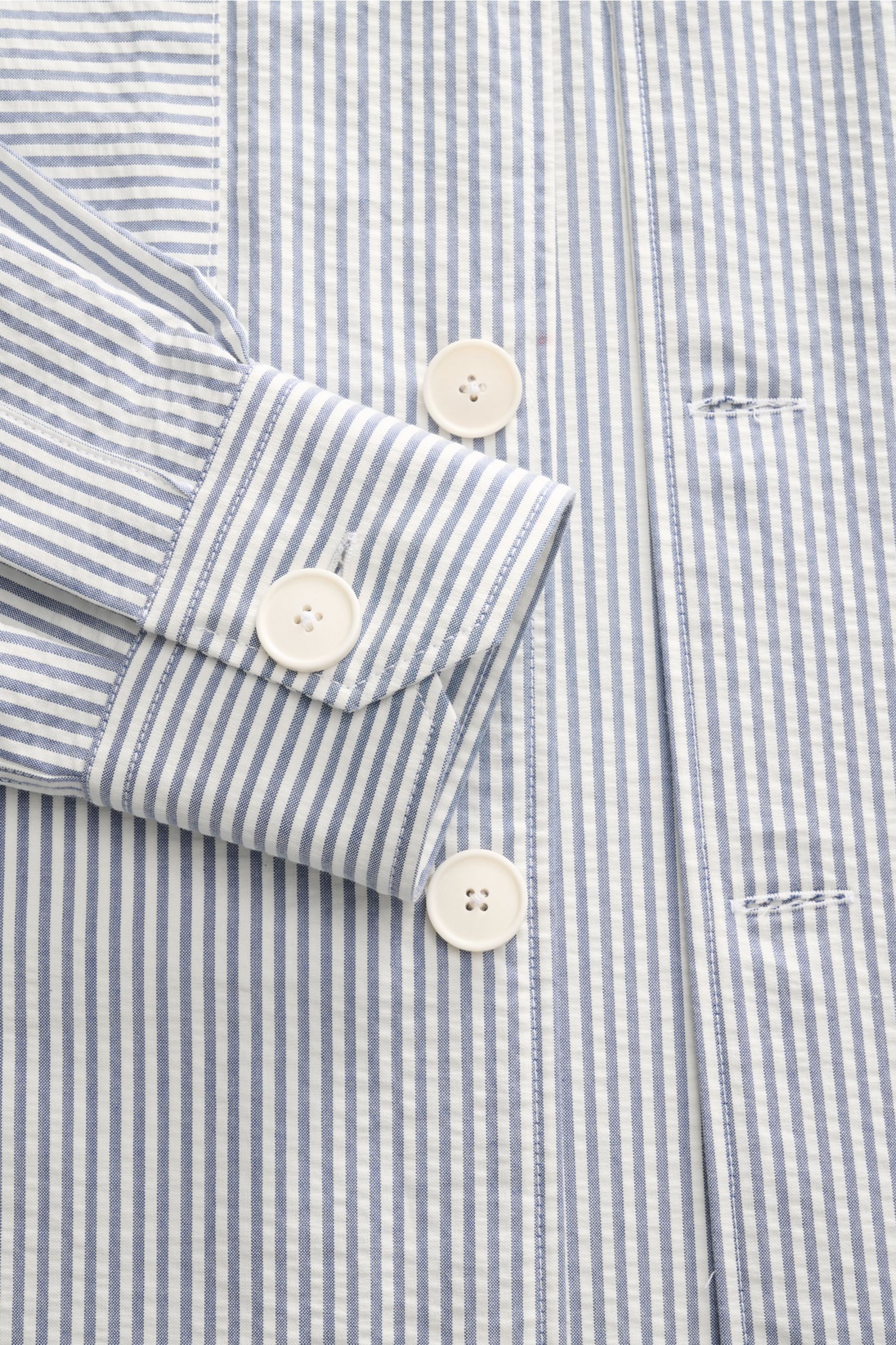 Doppiaa Seersucker-Hemd 'Aalassio' Haifisch-Kragen rauchblau shown from close-up front view, highlighting buttons, cuff, and blue-white stripes. Erste Wahl für mühelose Looks ist das Seersucker-Hemd 'Aalassio' aus reiner Baumwolle von DOPPIAA, das mit 