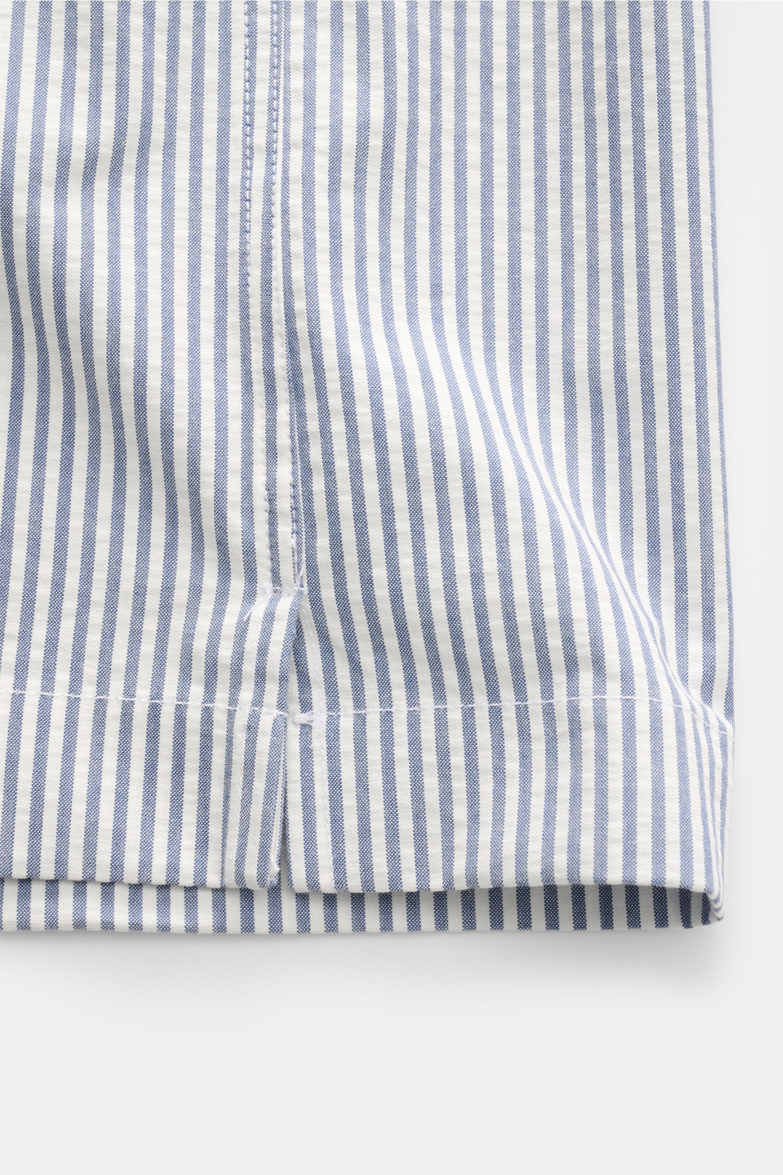 Close-up front view of the Doppiaa Seersucker-Hemd 'Aalassio' Haifisch-Kragen rauchblau, showing blue and white striped cotton fabric with crepe effect, stitch details, and rounded hem. Erste Wahl für mühelose Looks ist das Seersucker-Hemd 'Aalassio' a