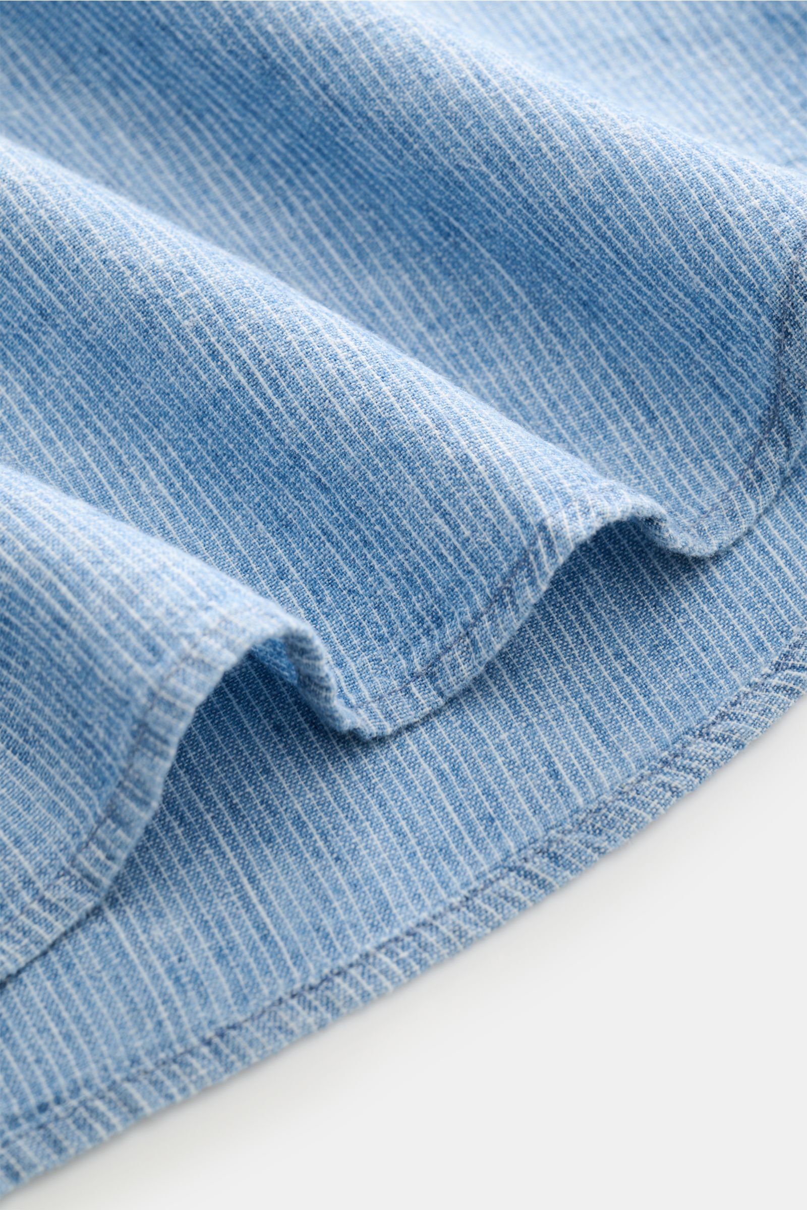 Nahaufnahme des feinen, leicht strukturierten Stoffs vom Guglielminotti Casual Hemd Haifisch-Kragen rauchblau gestreift, fotografiert aus seitlicher Perspektive, das den sommerlichen Leinen-Baumwoll-Mix und das gewebte Streifenmuster zeigt. 