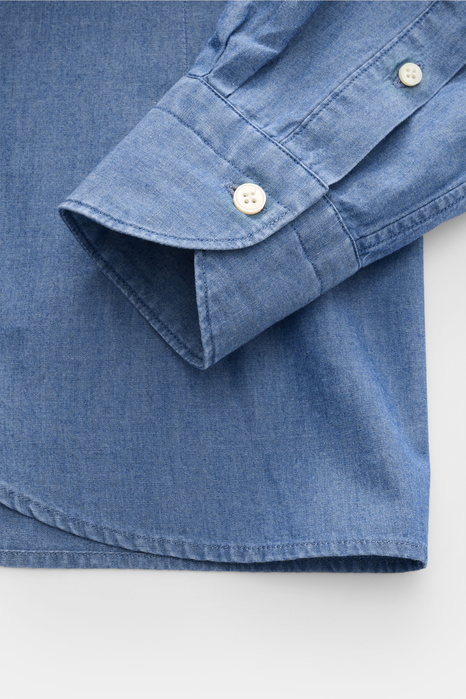 Guglielminotti Chambray shirt shark collar smoky blue shown from a close-up side angle, highlighting the pure cotton fabric, smooth feel, oversized fit, French button placket, classic barrel cuffs, and slightly rounded hem.