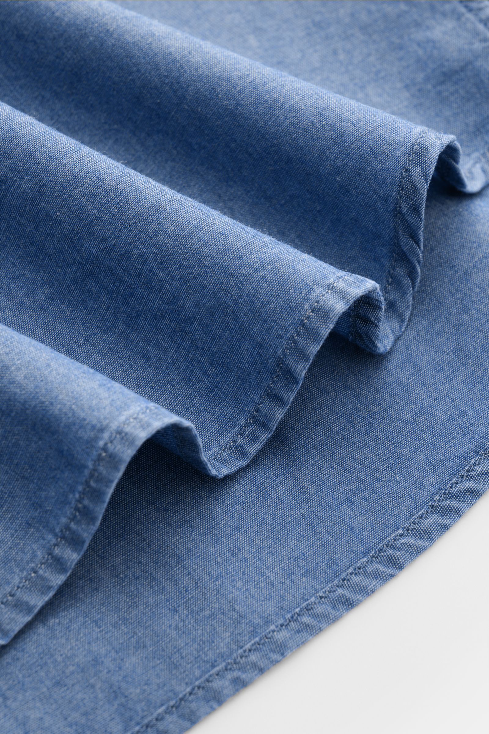 Close-up front-angle view of pure cotton fabric folds showing smooth texture of Guglielminotti Chambray shirt shark collar smoky blue in denim look.