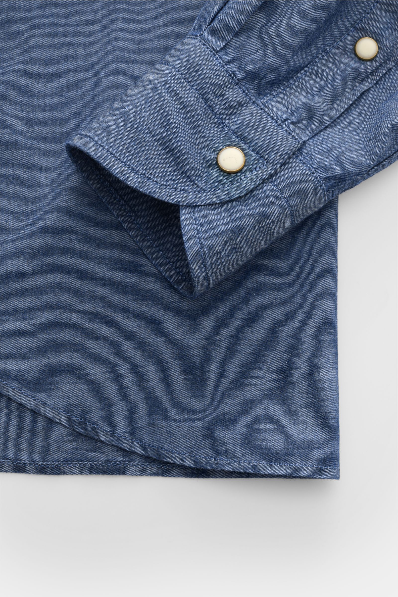 Guglielminotti Chambray shirt shark collar dark blue shown from a close-up top view of cuff and hem, pure cotton, smooth feel, oversized fit, patch breast pockets, patch button placket, classic barrel cuffs, slightly rounded hem 