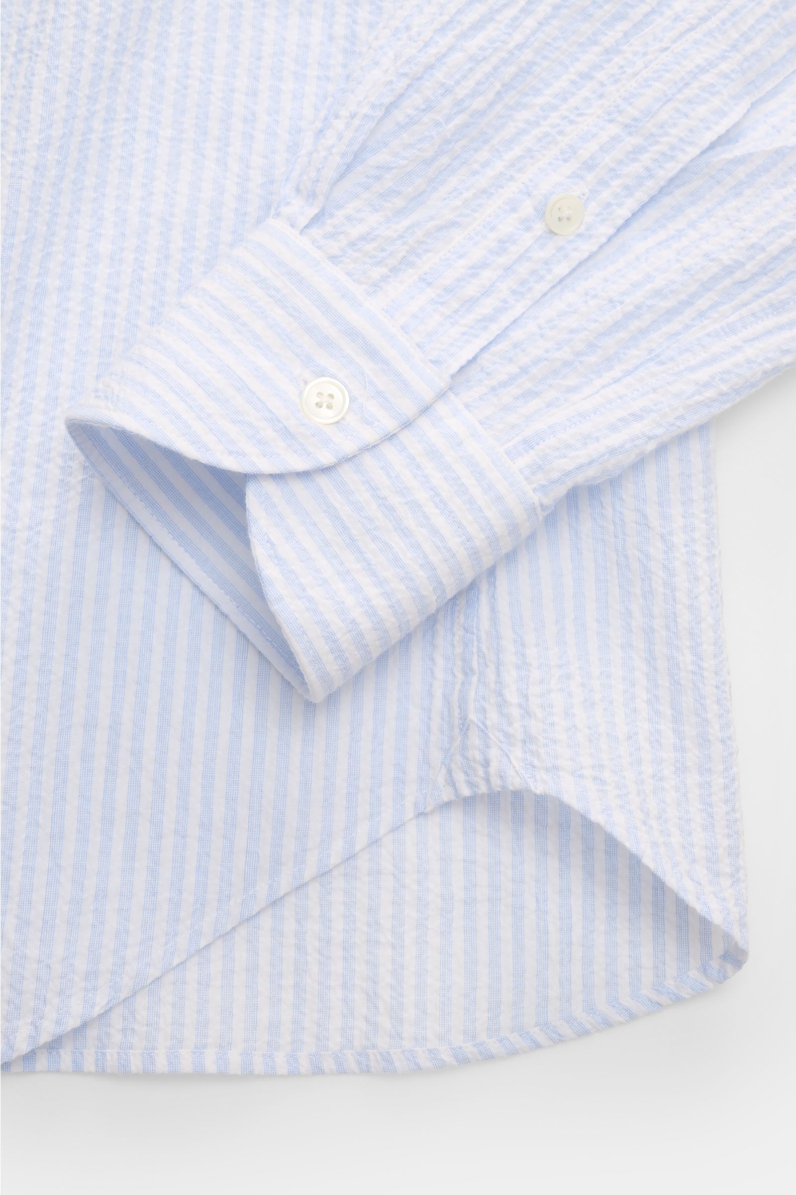 Nahaufnahme des Guglielminotti Casual Hemd Haifisch-Kragen hellblau/weiß gestreift, schmal, aus elastischer Baumwolle mit Crinkle-Effekt, Slim Fit, französischer Knopfleiste, Sportmanschetten und gerundetem Saum, seitlich fotografiert.