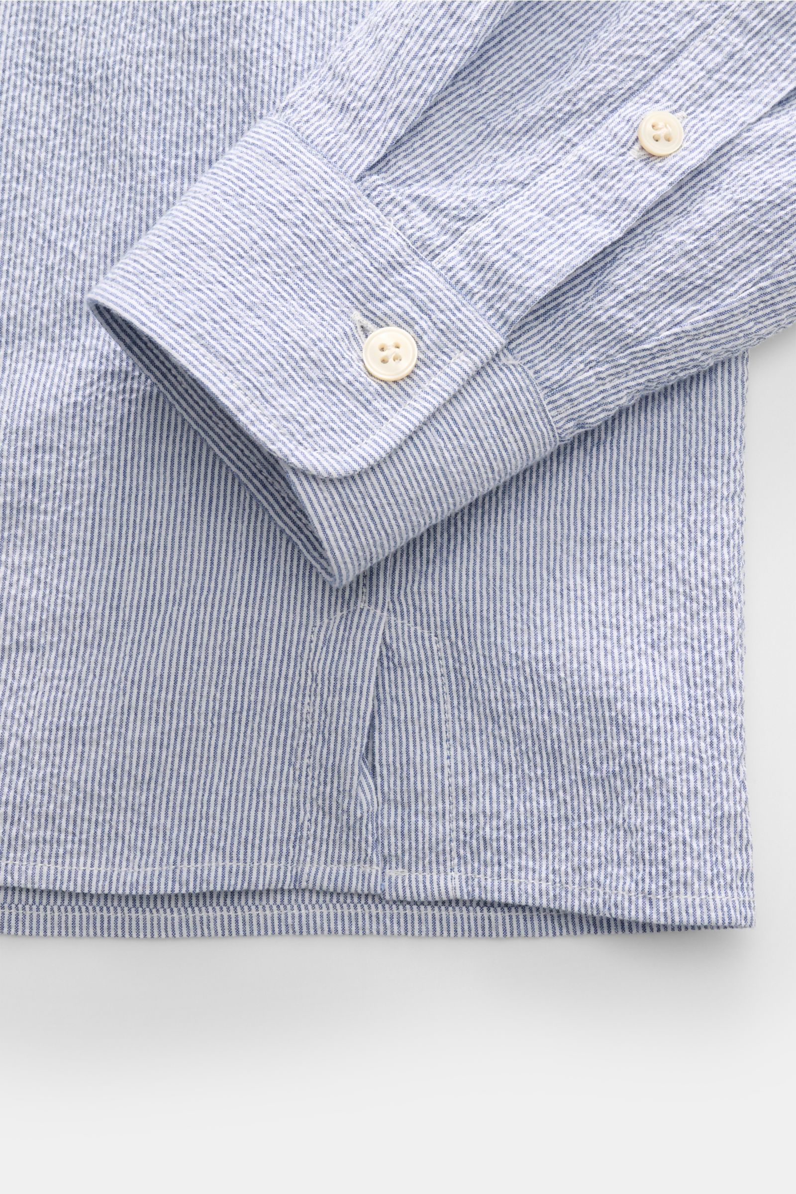Nahaufnahme des Guglielminotti Seersucker Popover-Hemd Haifisch-Kragen blau/weiß gestreift, Fokus auf Manschette und Saum, elastische Baumwolle, Slim Fit, italienische Schneiderkunst.