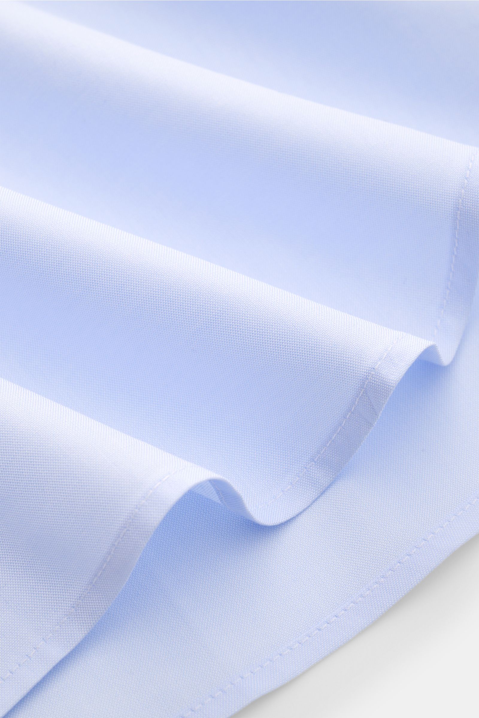 Guglielminotti Casual Hemd Haifisch-Kragen hellblau, Detailaufnahme der feinen Popeline-Baumwolle mit glattem Griff und Saum, schräg von oben.