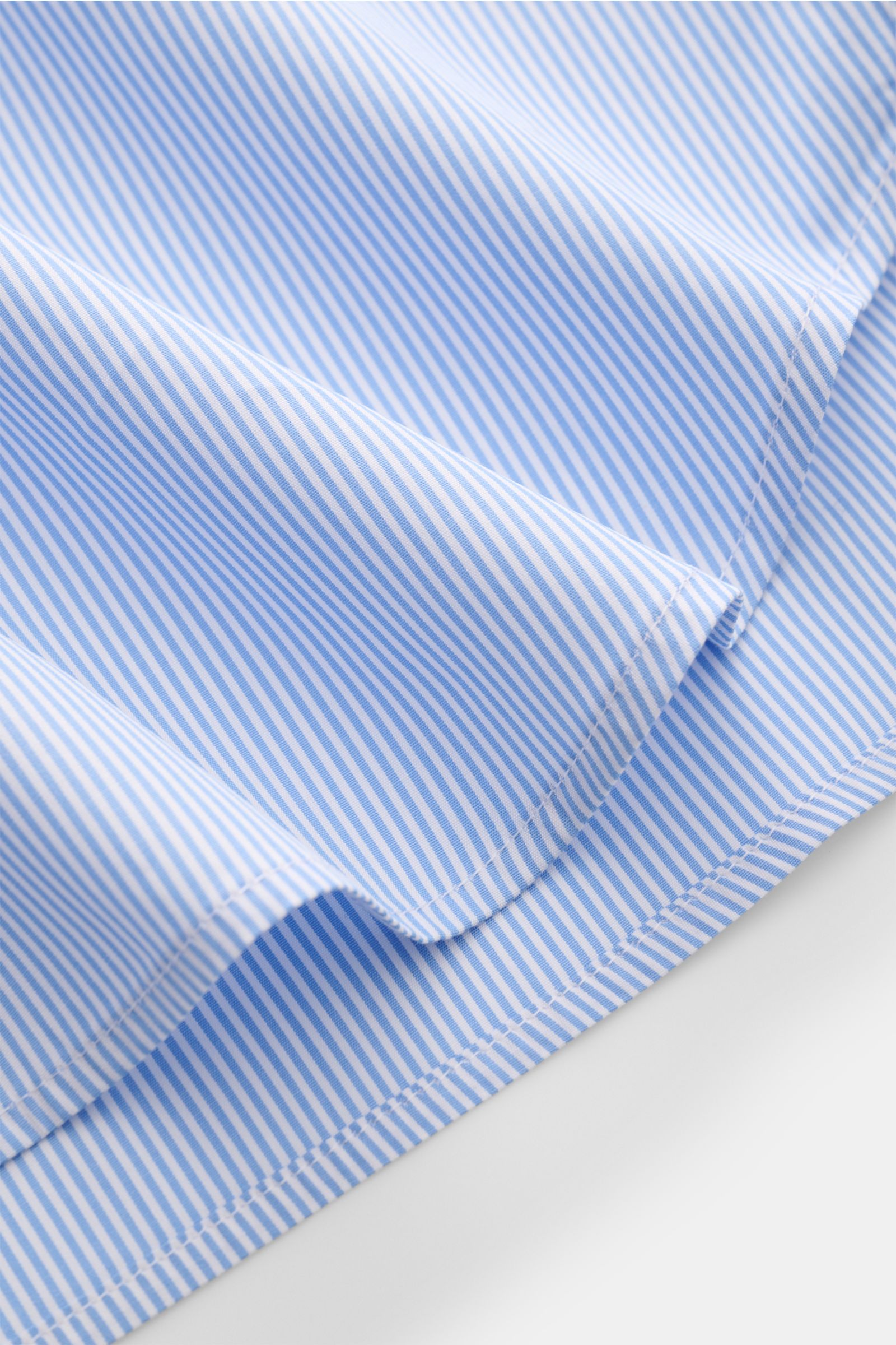 Close-up of Guglielminotti Casual shirt shark collar blue/white striped showing pure cotton fabric, smooth texture, and rounded hem from an angled perspective. 
