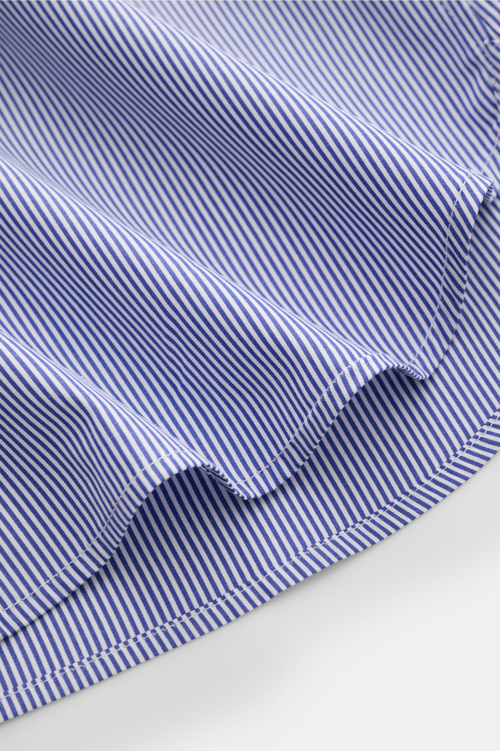 Nahaufnahme des gerundeten Saumverlaufs des Guglielminotti Casual Hemd Haifisch-Kragen dunkelblau/weiß gestreift aus reiner Baumwolle, Slim Fit, glattem Griff, französischer Knopfleiste mit Perlmuttknöpfen und klassischer Sportmanschette, fotografiert aus