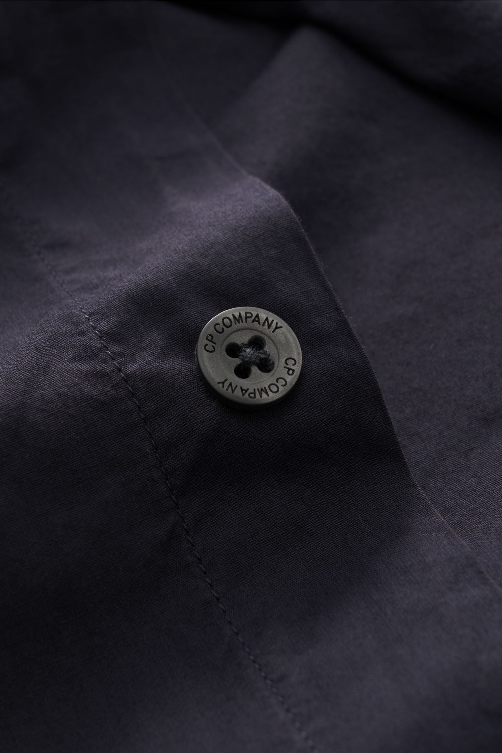 Nahaufnahme des navyfarbenen C.P. Company Casual Hemd schmaler Kragen navy mit Knopf und feiner Baumwollstruktur, Detail von Frontansicht.