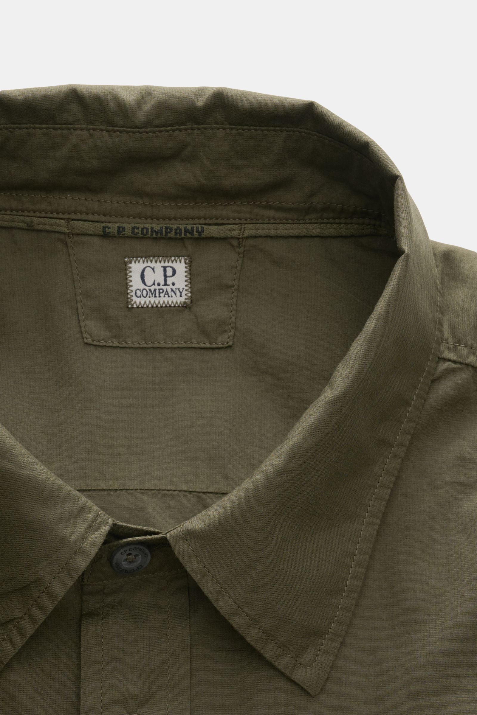 C.P. Company Casual Hemd schmaler Kragen dark olive, Detailaufnahme von oben, reine Baumwolle, weicher Griff, garment dyed, schmaler Kragen, Knopfleiste und Markenlabel sichtbar
