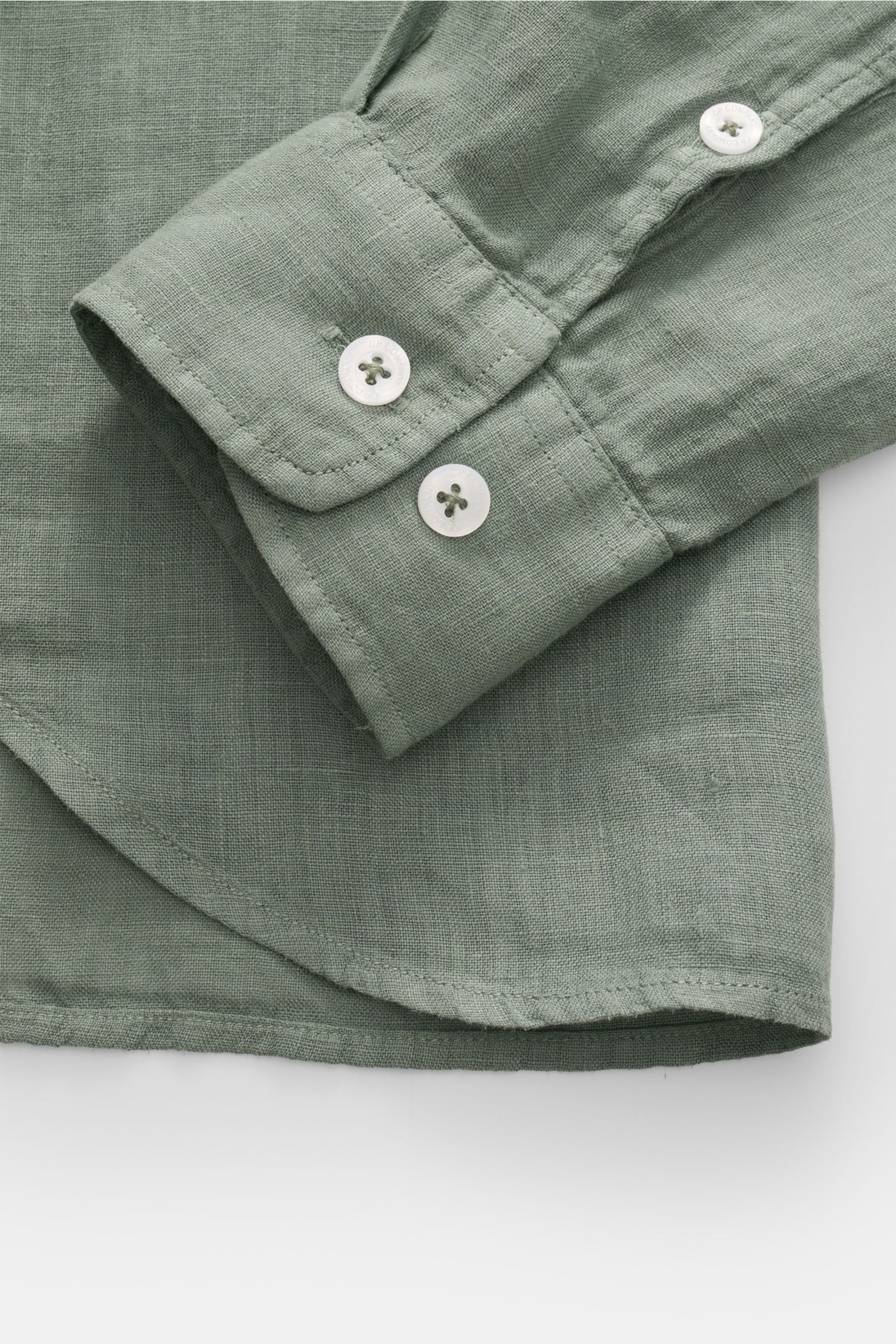 Close-up front view of the cuff and hem of the C.P. Company Linen shirt slim collar sage in pure linen, garment-dyed sage green with classic barrel cuffs, patch button placket, two white buttons, rounded hem with slightly elongated back, and soft textured