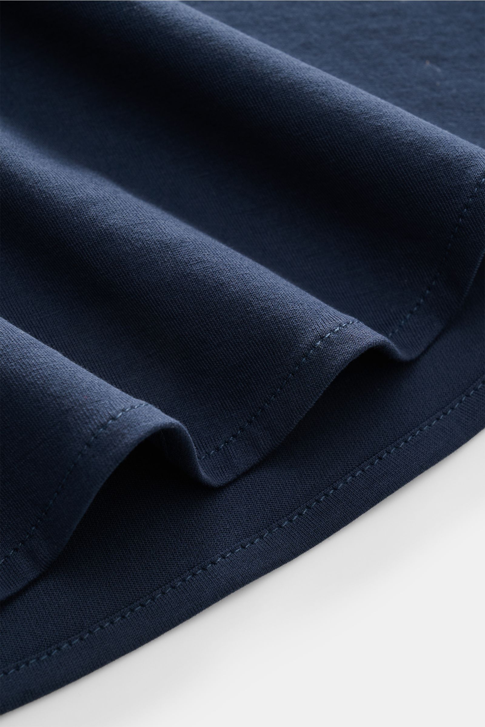 Close-up of dark blue fabric folds showing texture and stitching from a top-down perspective, highlighting Stefan Brandt Jersey-Hemd 'Otis' Haifisch-Kragen dunkelblau.

Description: 
Flexibler, geschmeidiger Jersey aus reiner Pima-Baumwolle lässt das c
