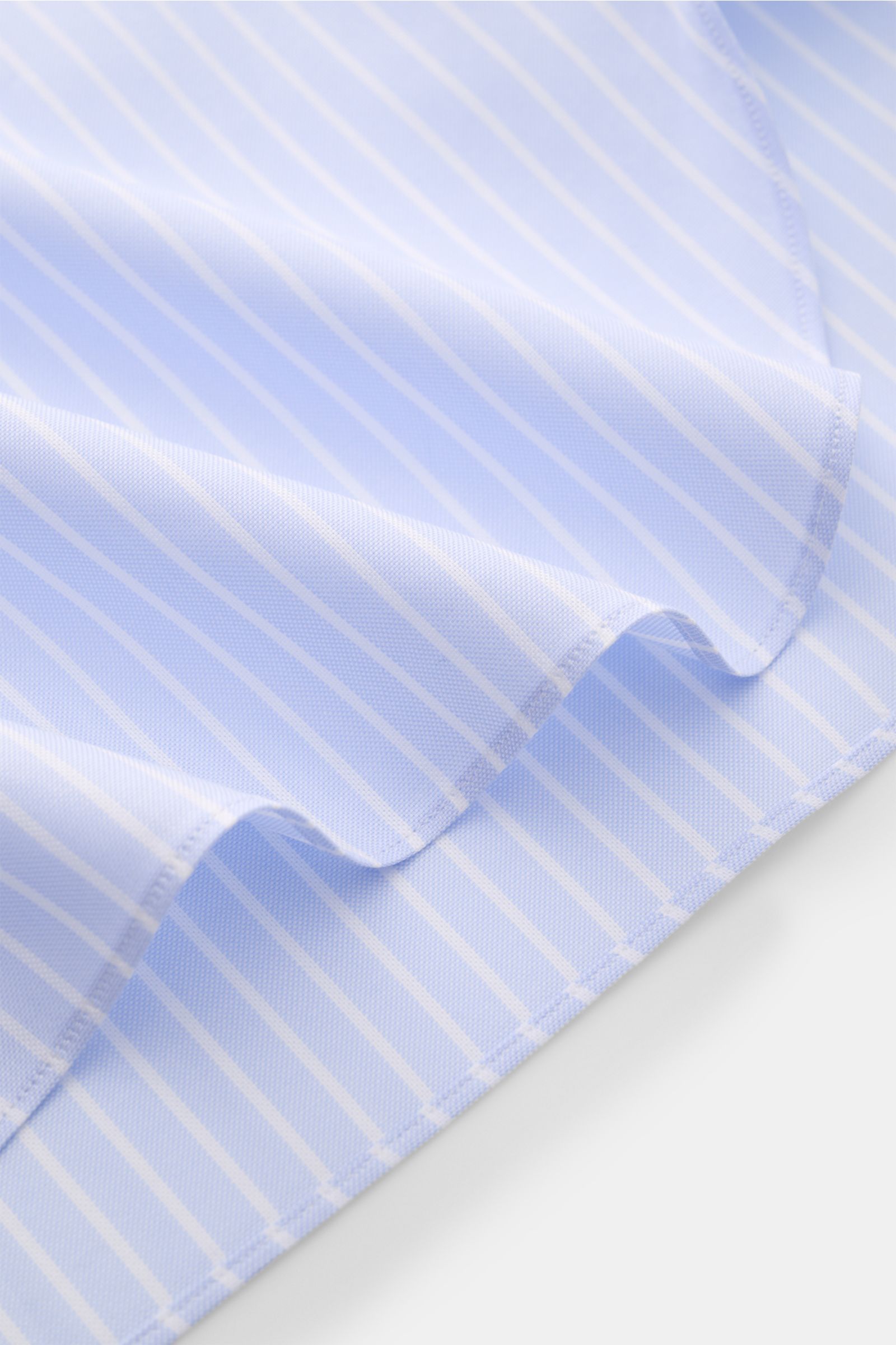 Giampaolo Oxford-Hemd Button-Down-Kragen hellblau/weiß gestreift shown in close-up from an angled top-down view, highlighting fine Oxford cotton fabric, slim fit, button-down collar, classic sport cuff, back waist darts, and rounded hem. Klassiker vom 