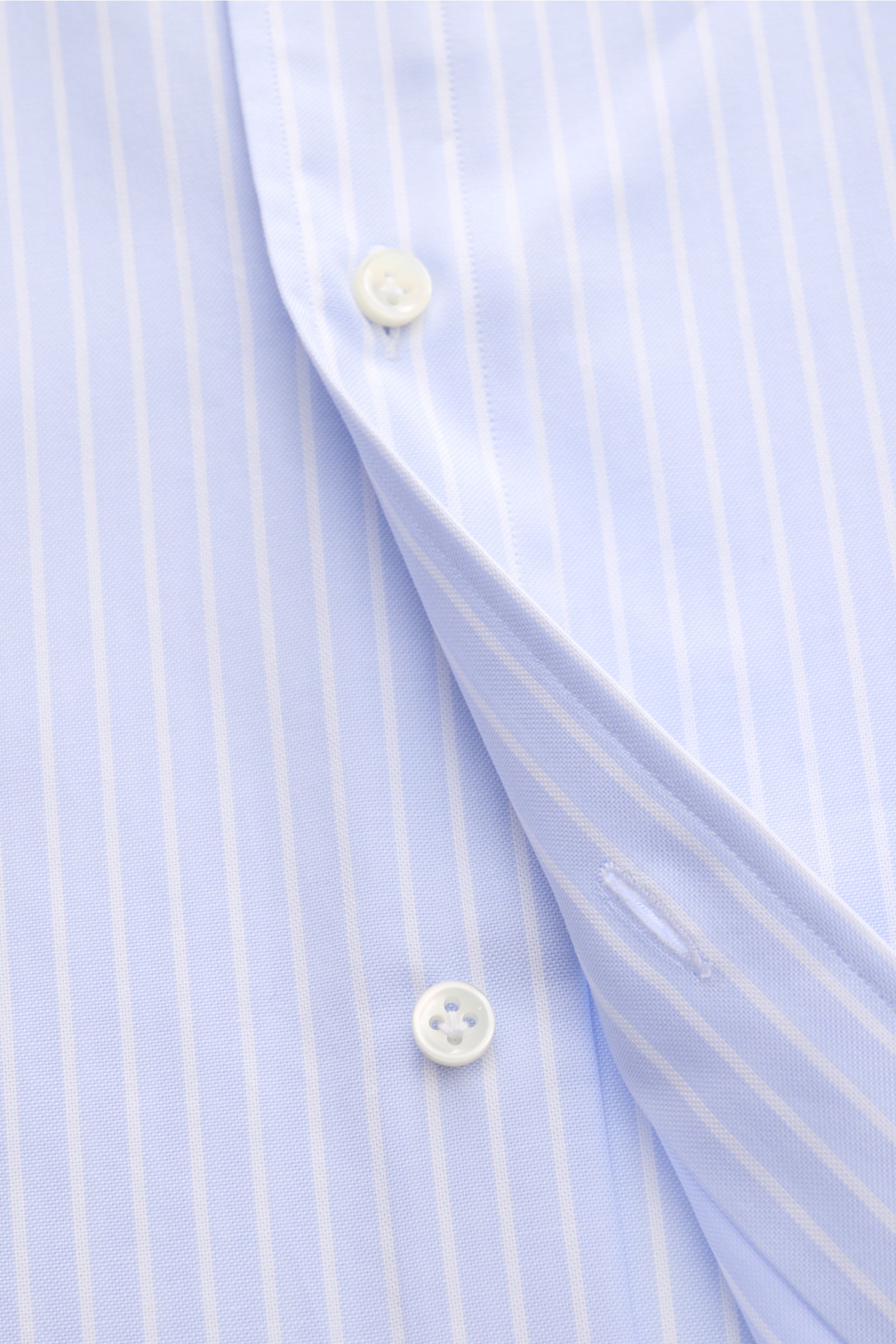 Close-up front view of the Giampaolo Oxford-Hemd Button-Down-Kragen hellblau/weiß gestreift, a slim fit classic Italian Oxford shirt with button-down collar, pure cotton fabric, structured texture, button placket, sport cuffs, back waist darts, and rounde