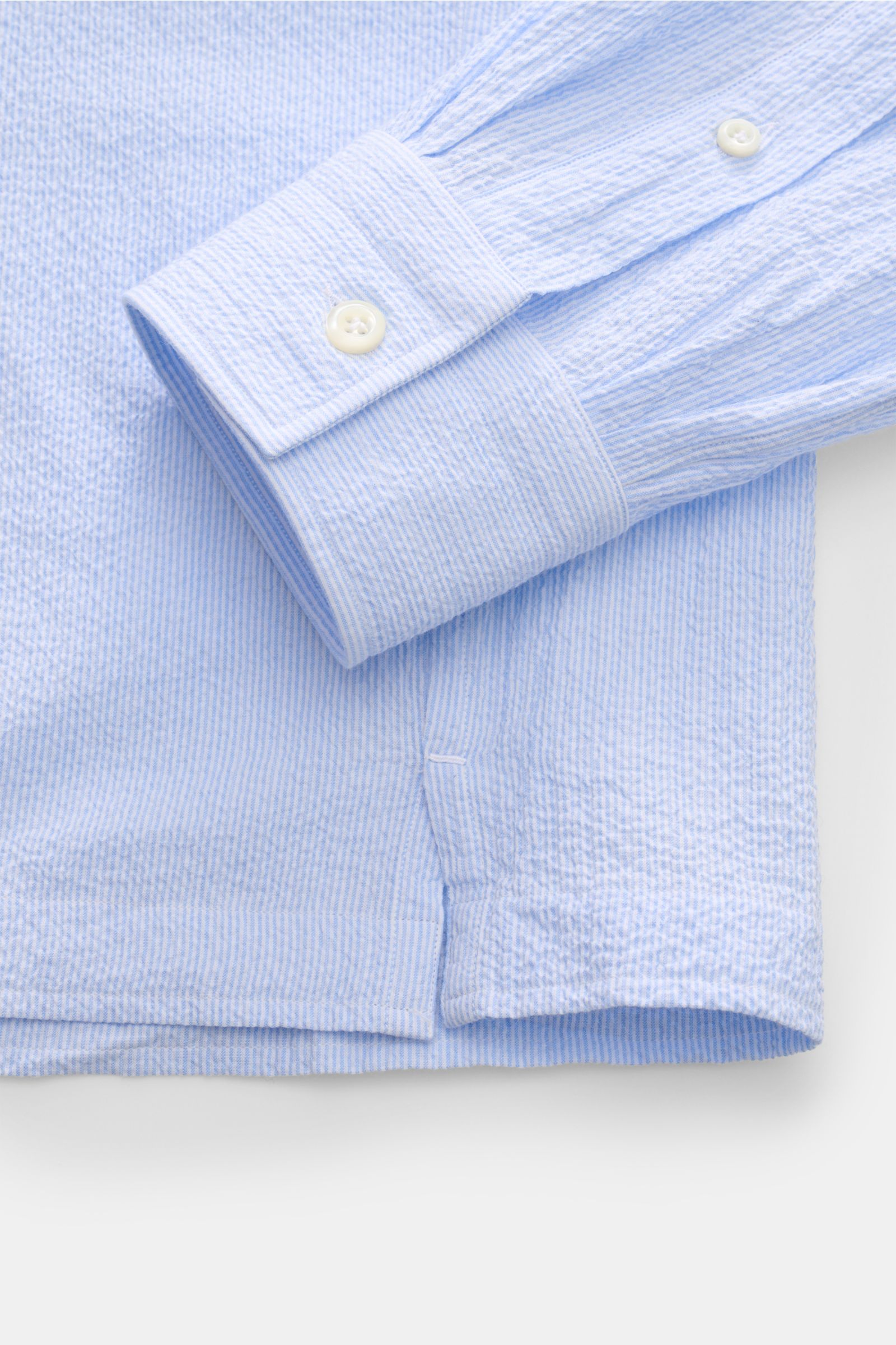 Nahaufnahme des Giampaolo Seersucker Popover-Hemd Haifisch-Kragen hellblau/weiß gestreift, Detail von Manschette, Knopfleiste und Saum aus leicht elastischem Baumwoll-Seersucker.