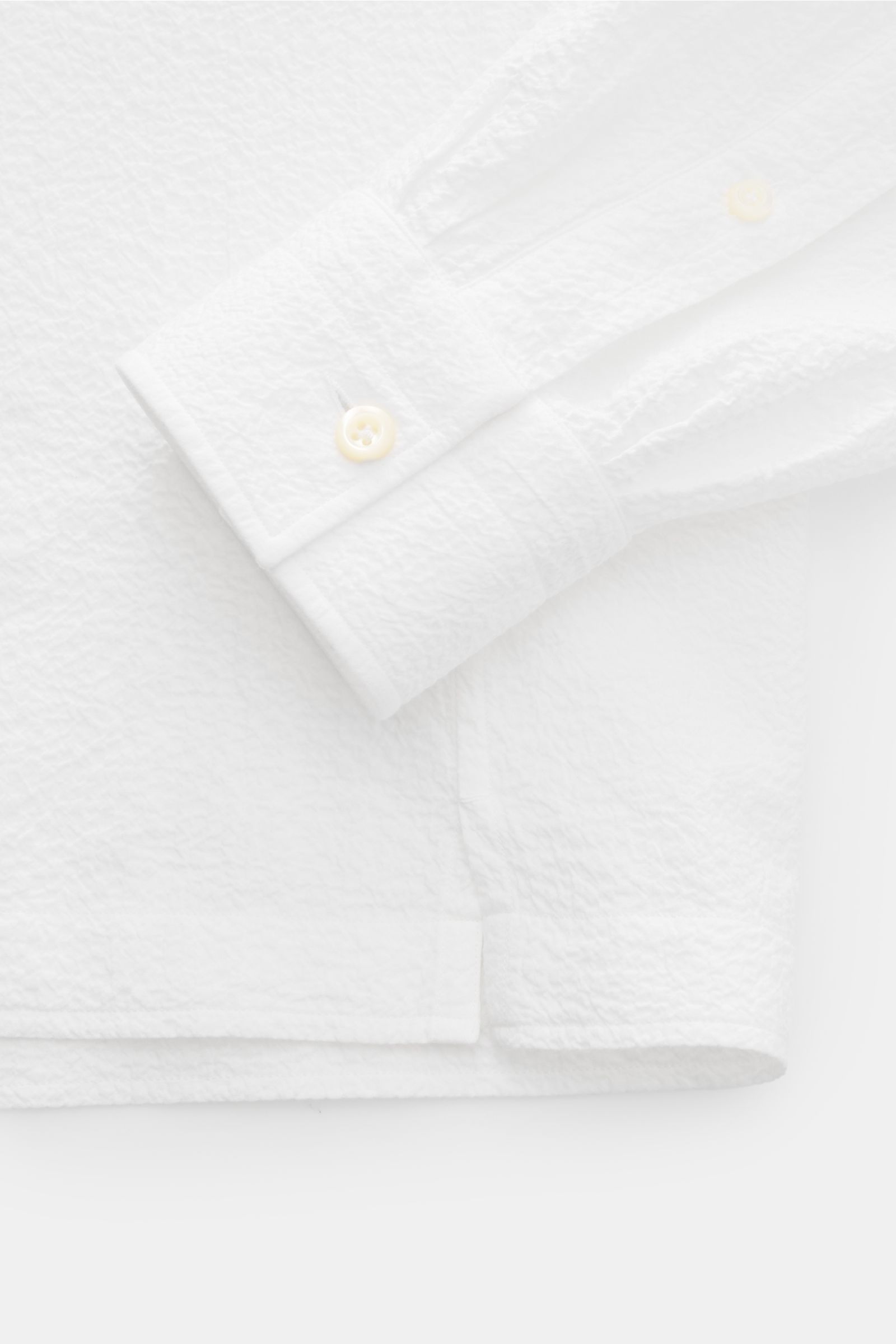 Nahaufnahme des weißen Giampaolo Seersucker Popover-Hemd Haifisch-Kragen mit klassischer Sportmanschette, Quetschfalte und geradem Saum, fotografiert von oben.