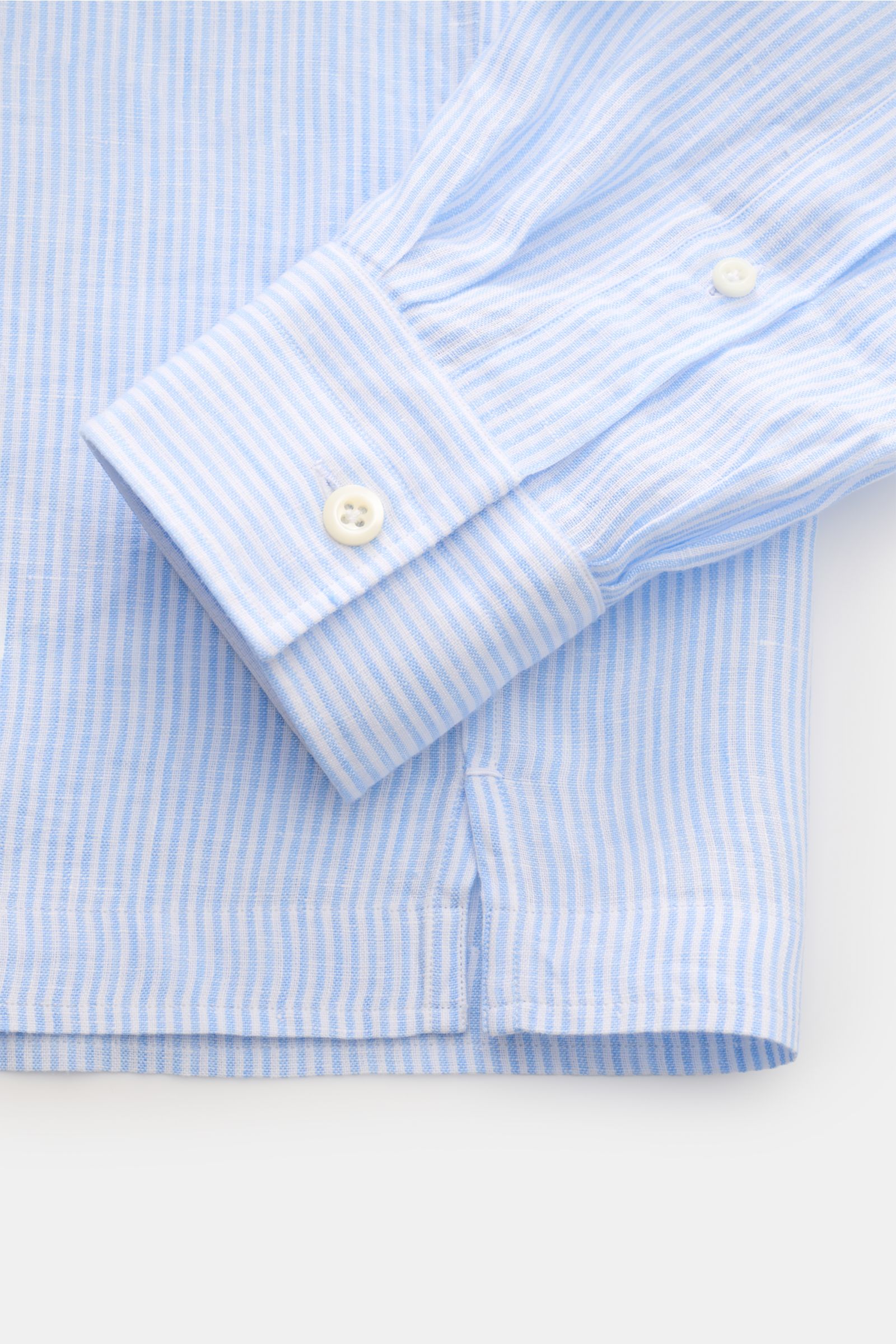 Close-up image from above showing the cuff and hem details of the Giampaolo Popover-Leinenhemd Haifisch-Kragen hellblau/weiß gestreift, a classic Italian linen shirt in light blue and white stripes featuring a shark collar, regular fit, a light textured l