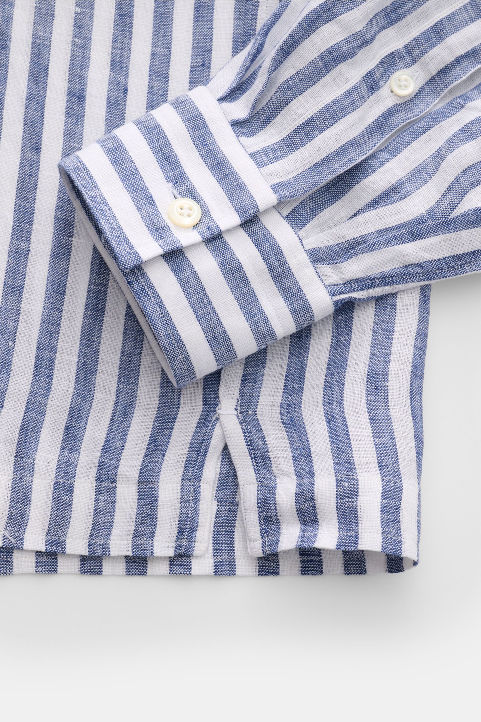 Close-up image of the cuff and lower side hem from a top-down perspective showing the navy and white striped fabric of the Giampaolo Popover-Leinenhemd Haifisch-Kragen navy/weiß gestreift. Klassiker mit Twist vom italienischen Hemdenexperten GIAMPAOLO: Di