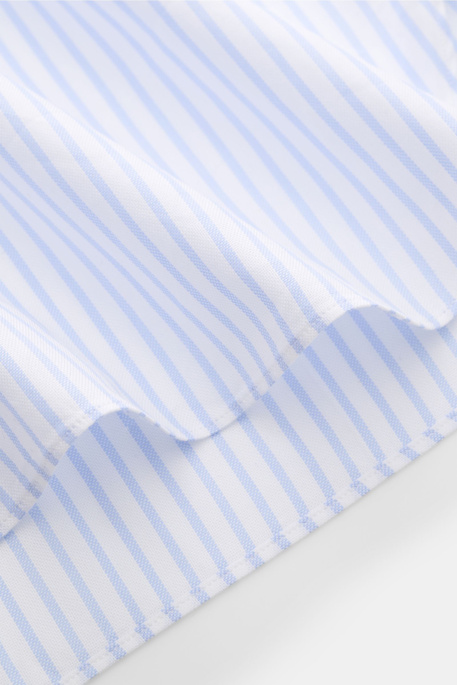 Nahaufnahme des Saums vom Giampaolo Oxford-Hemd Haifisch-Kragen weiß/hellblau gestreift aus reiner Baumwolle mit Slim Fit.