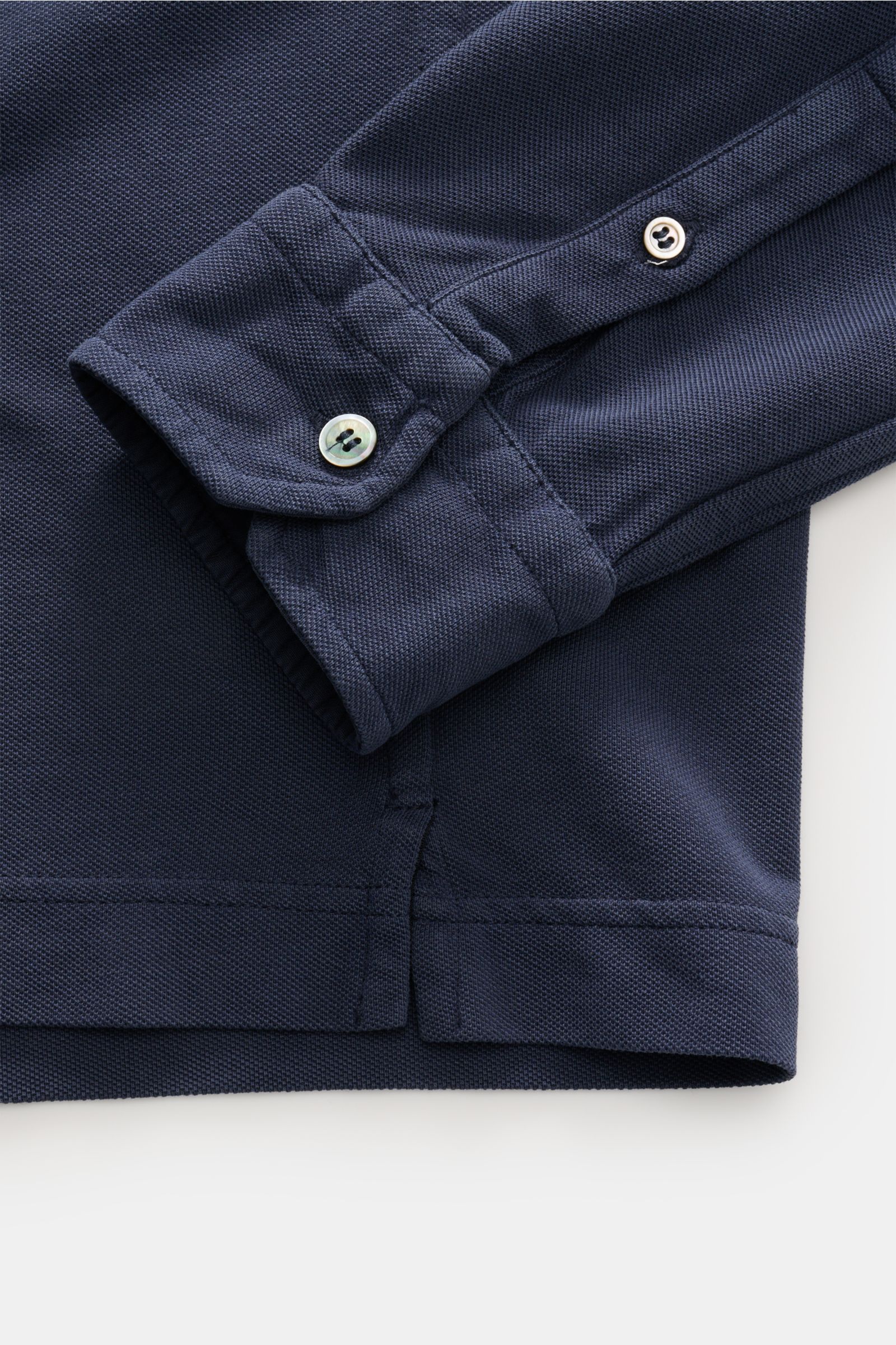 Nahaufnahme des Ärmels und Saums eines dunkelblauen Della Ciana Piqué-Hemd Haifisch-Kragen, gefertigt aus Baumwoll-Piqué mit strukturierter Oberfläche, garment dyed, Regular Fit, mit französischer Knopfleiste, klassischer Sportmanschette und kurzen Saumsc