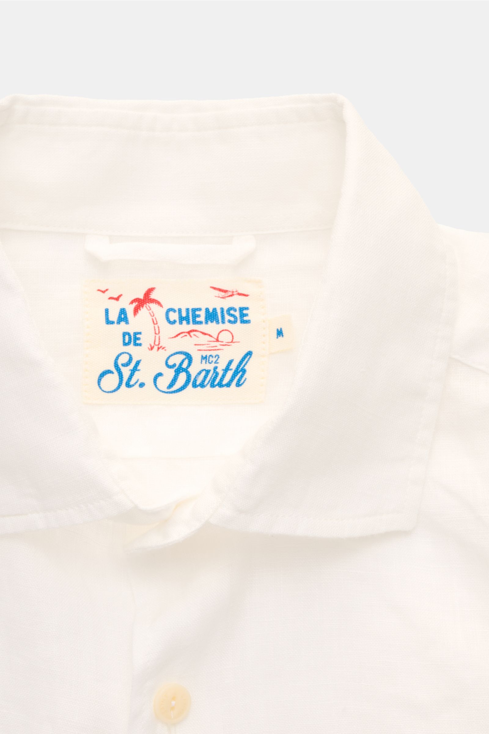 Close-up front view of MC2 Saint Barth Linen shirt 'Pamplona' shark collar white, showing collar and label on lightweight linen fabric.

With this airy, lightweight shirt in pure linen, MC2 SAINT BARTH brings us a perfect piece for casual summer looks.