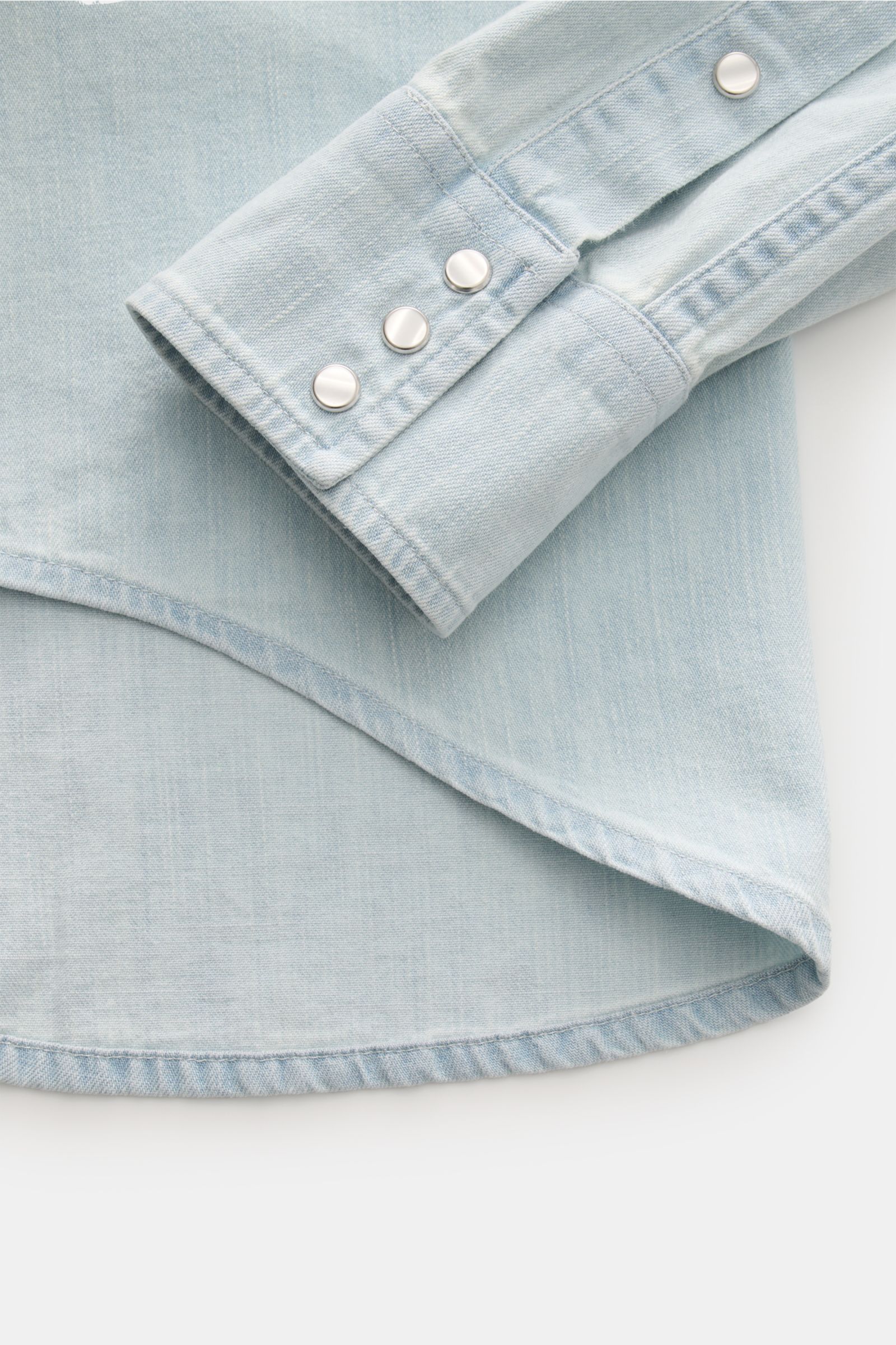 Close-up view of the sleeve and curved hem of the Dondup Jeanshemd Kent-Kragen pastellblau in soft pastel blue denim with snap buttons.

Description: Modernes Denim Statement: Das Jeanshemd von DONDUP präsentiert einen Klassiker in edler, moderner Ausf