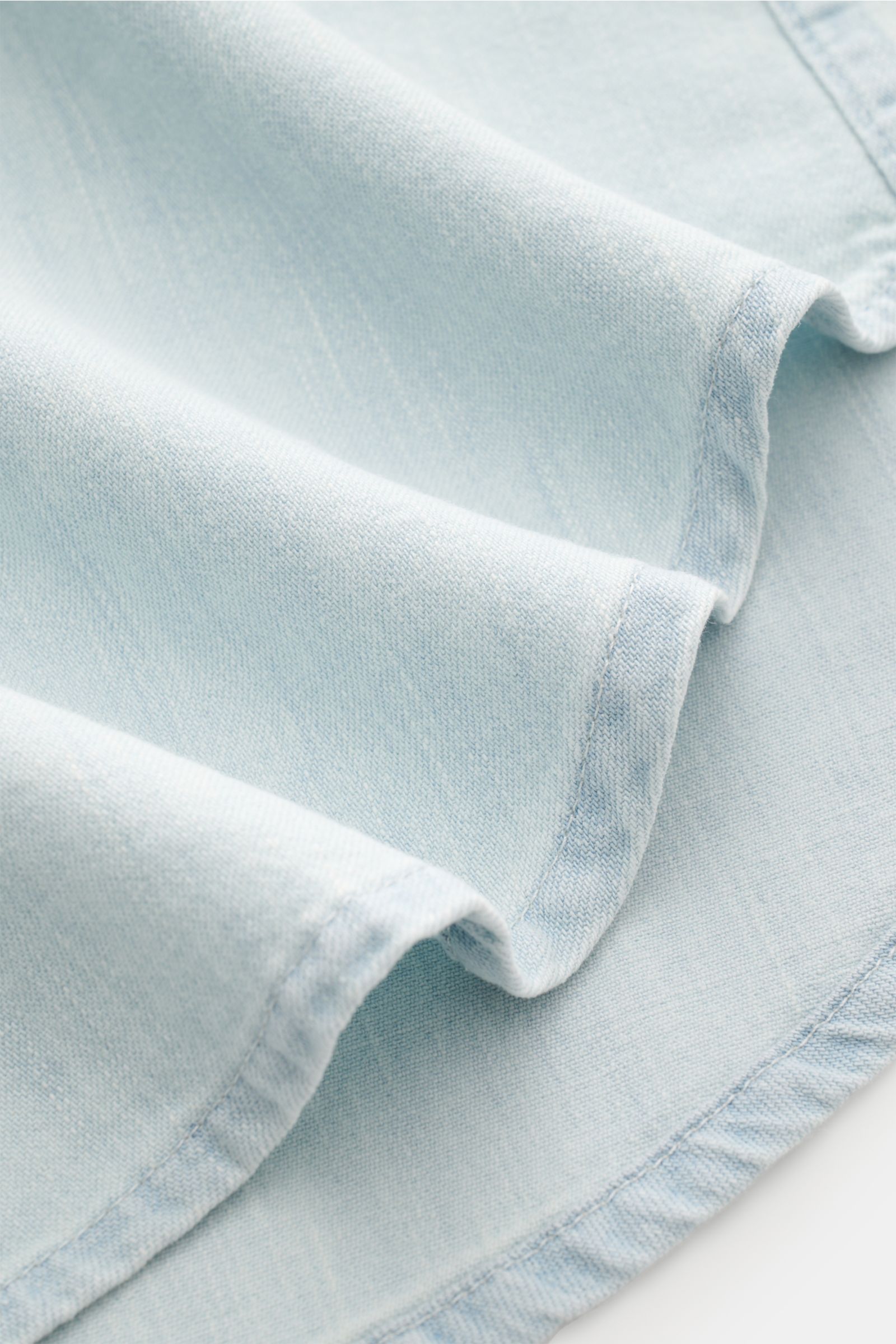 Close-up front view of Dondup Jeanshemd Kent-Kragen pastellblau in soft pastel blue denim fabric with visible stitching and folded hem.

Description: Modernes Denim Statement: Das Jeanshemd von DONDUP präsentiert einen Klassiker in edler, moderner Ausf