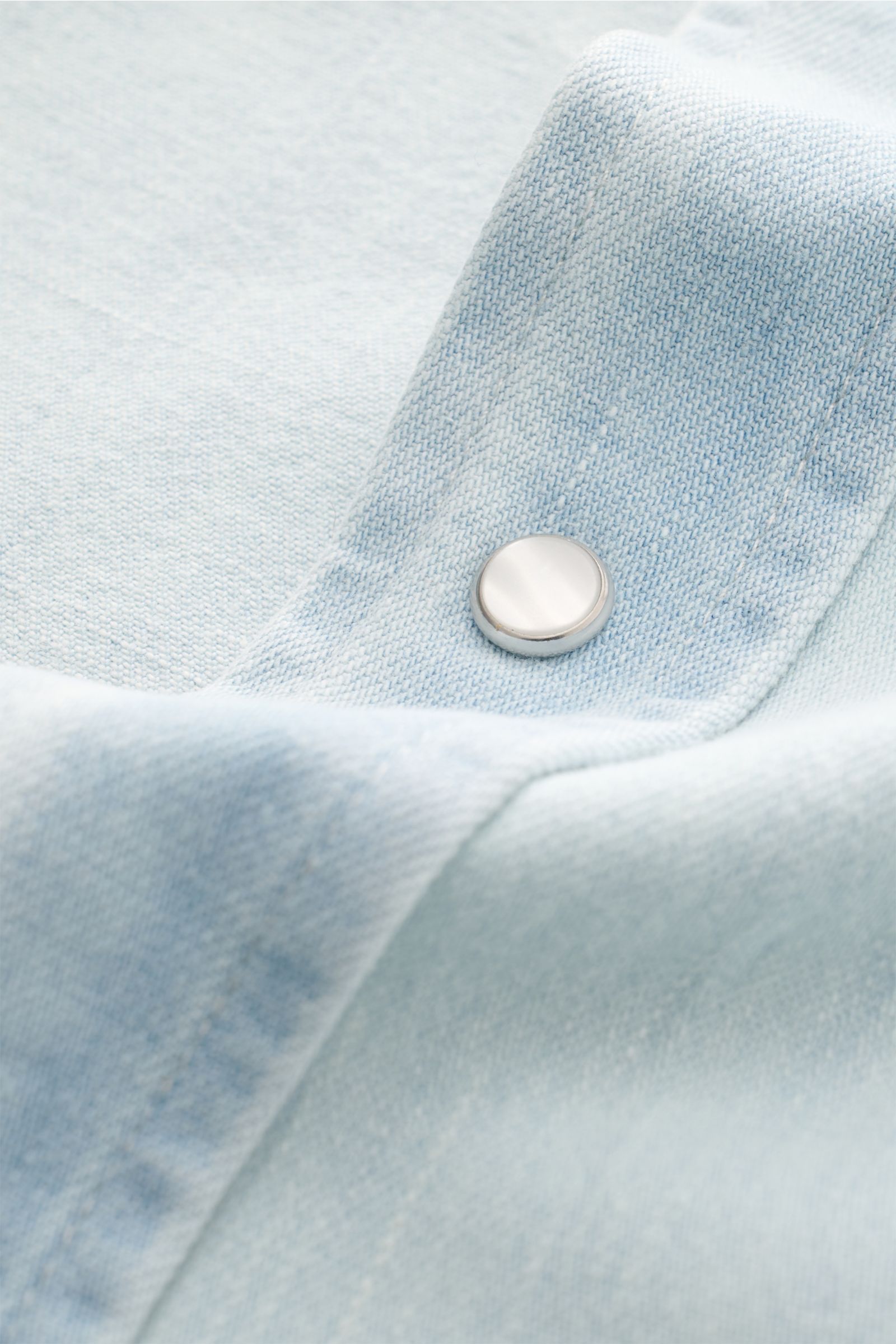 Close-up front angle of Dondup Jeanshemd Kent-Kragen pastellblau in soft pastel blue denim, showing snap button detail and fabric texture. Modernes Denim Statement: Das Jeanshemd von DONDUP präsentiert einen Klassiker in edler, moderner Ausführung – ein v