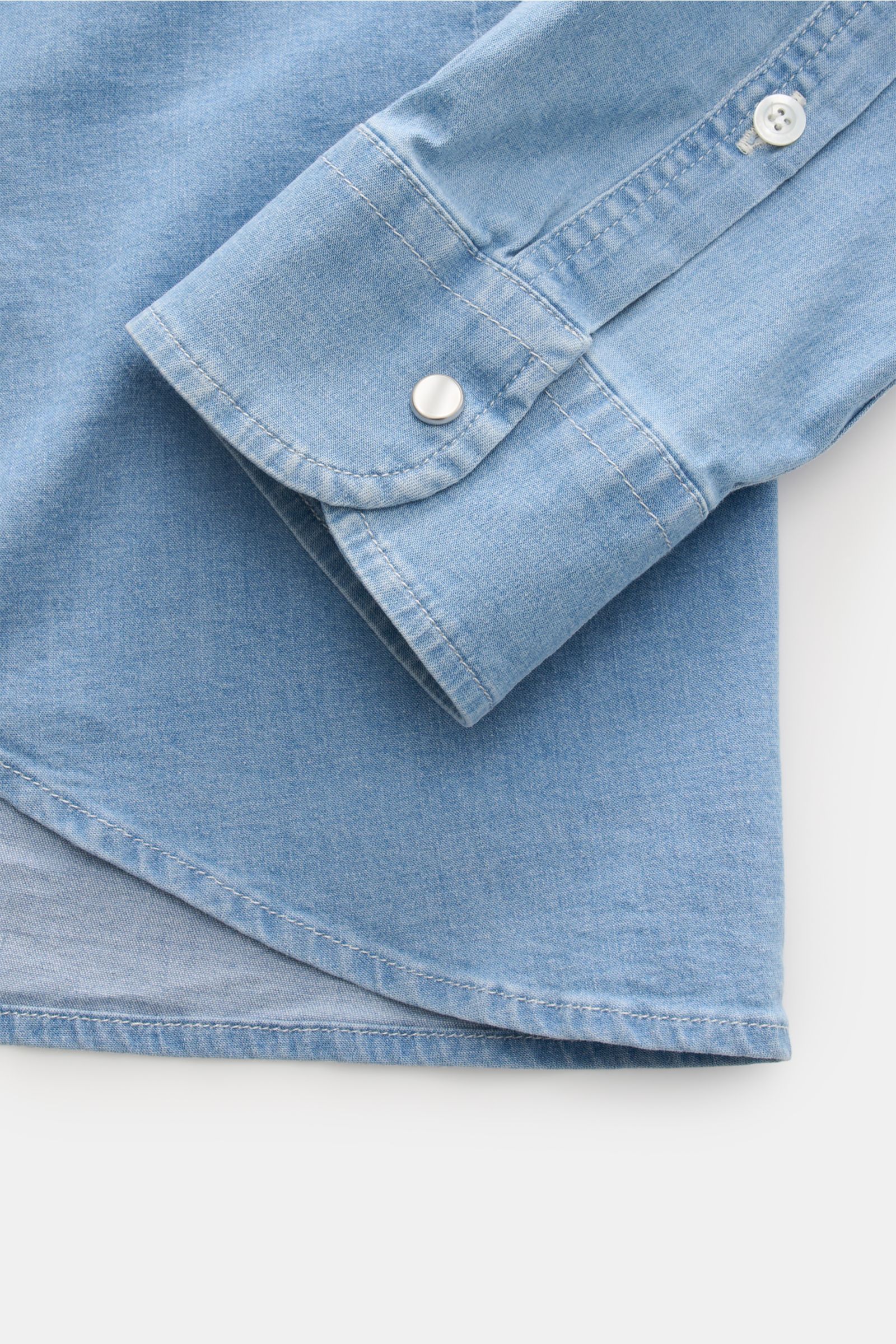 Close-up front view of Dondup Jeanshemd Kent-Kragen rauchblau showing the sleeve cuff with snap button and rounded hem, made of soft elastic cotton. Modernes Denim Statement: Das Jeanshemd von DONDUP präsentiert einen Klassiker in edler, moderner Ausführu