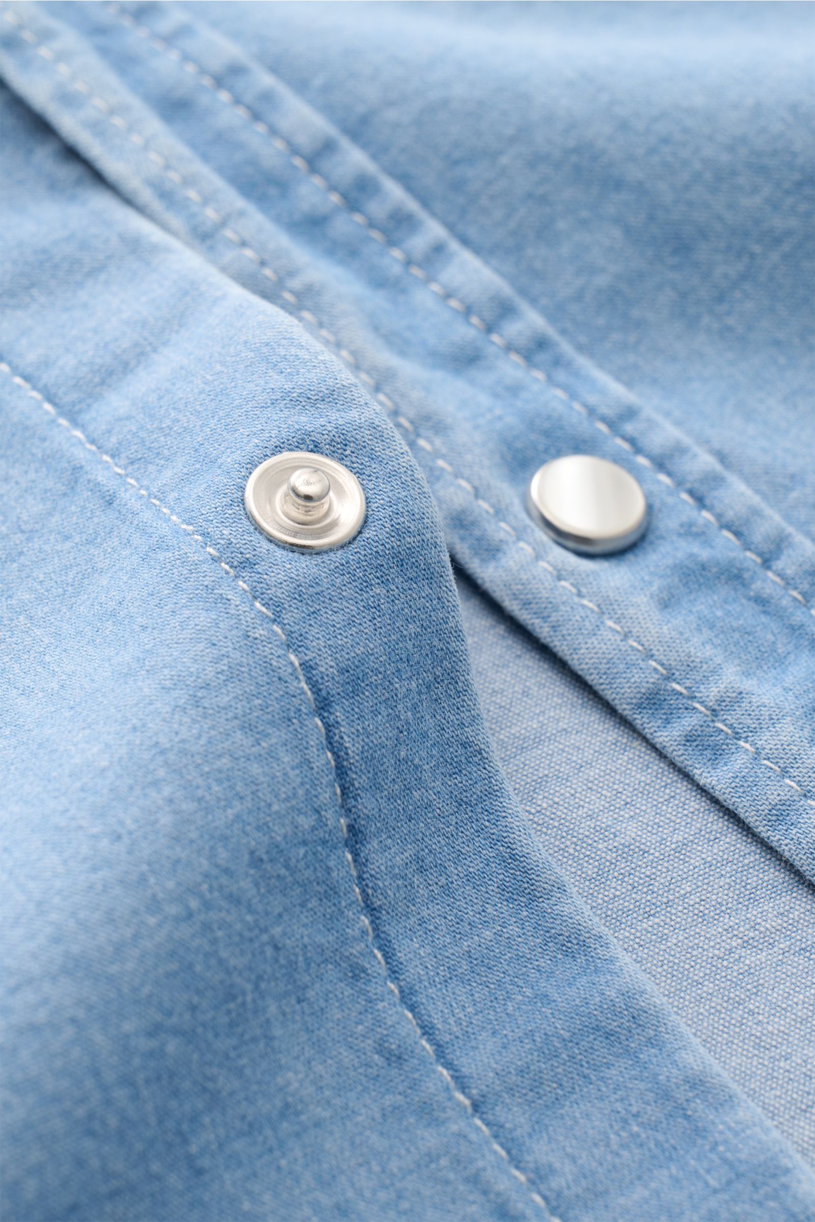 Close-up front view of Dondup Jeanshemd Kent-Kragen rauchblau showing snap button and soft elastic cotton fabric with smooth texture. Modernes Denim Statement: Das Jeanshemd von DONDUP präsentiert einen Klassiker in edler, moderner Ausführung – ein vielse