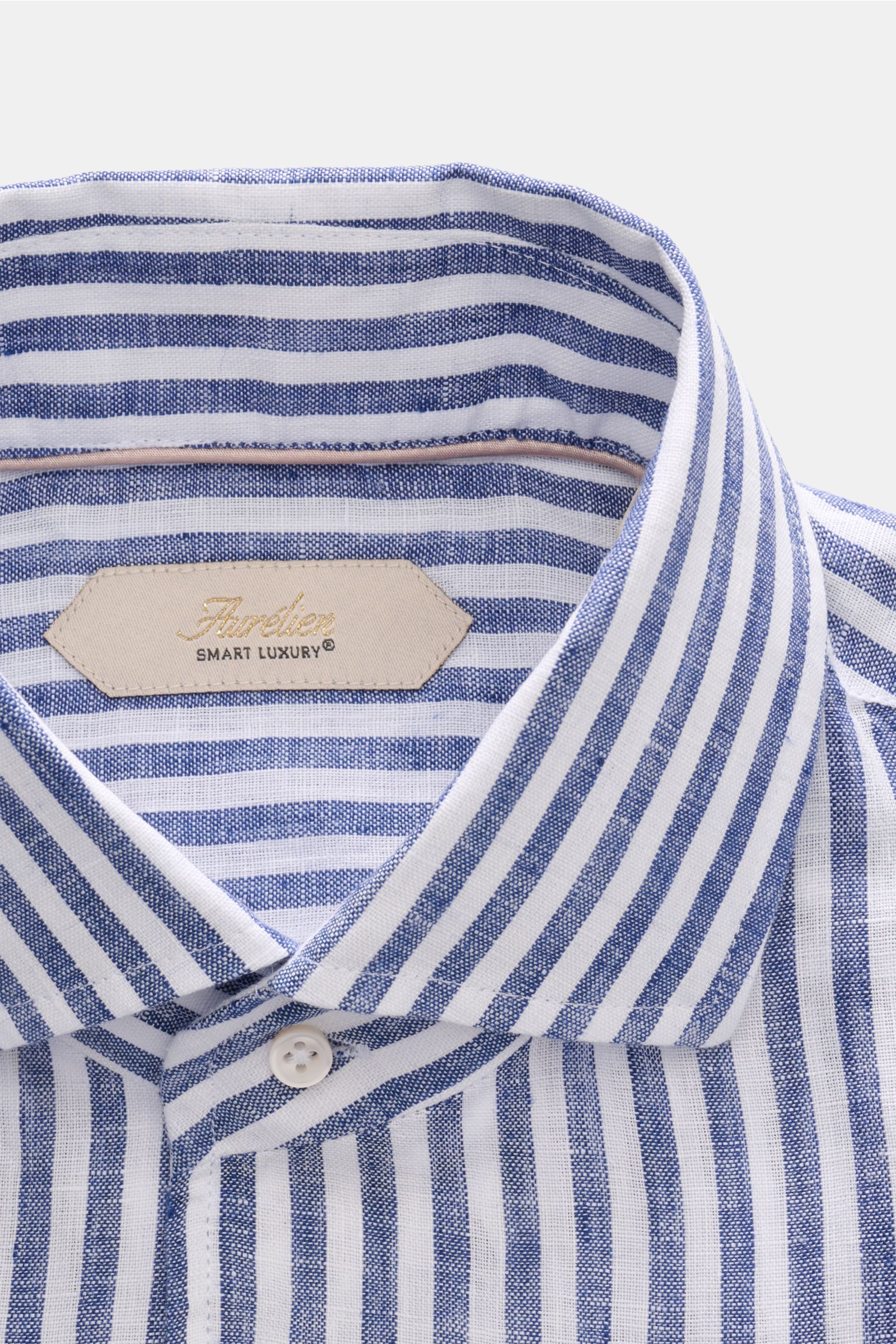 Close-up front view of the Aurélien Leinenhemd Haifisch-Kragen navy/weiß gestreift showing the shark collar, French placket, and fabric label. Ein wenig Urlaubsfeeling gefällig? Das vielseitig einsetzbare Hemd der Marke AURÉLIEN wird mit seinem feinen Lei