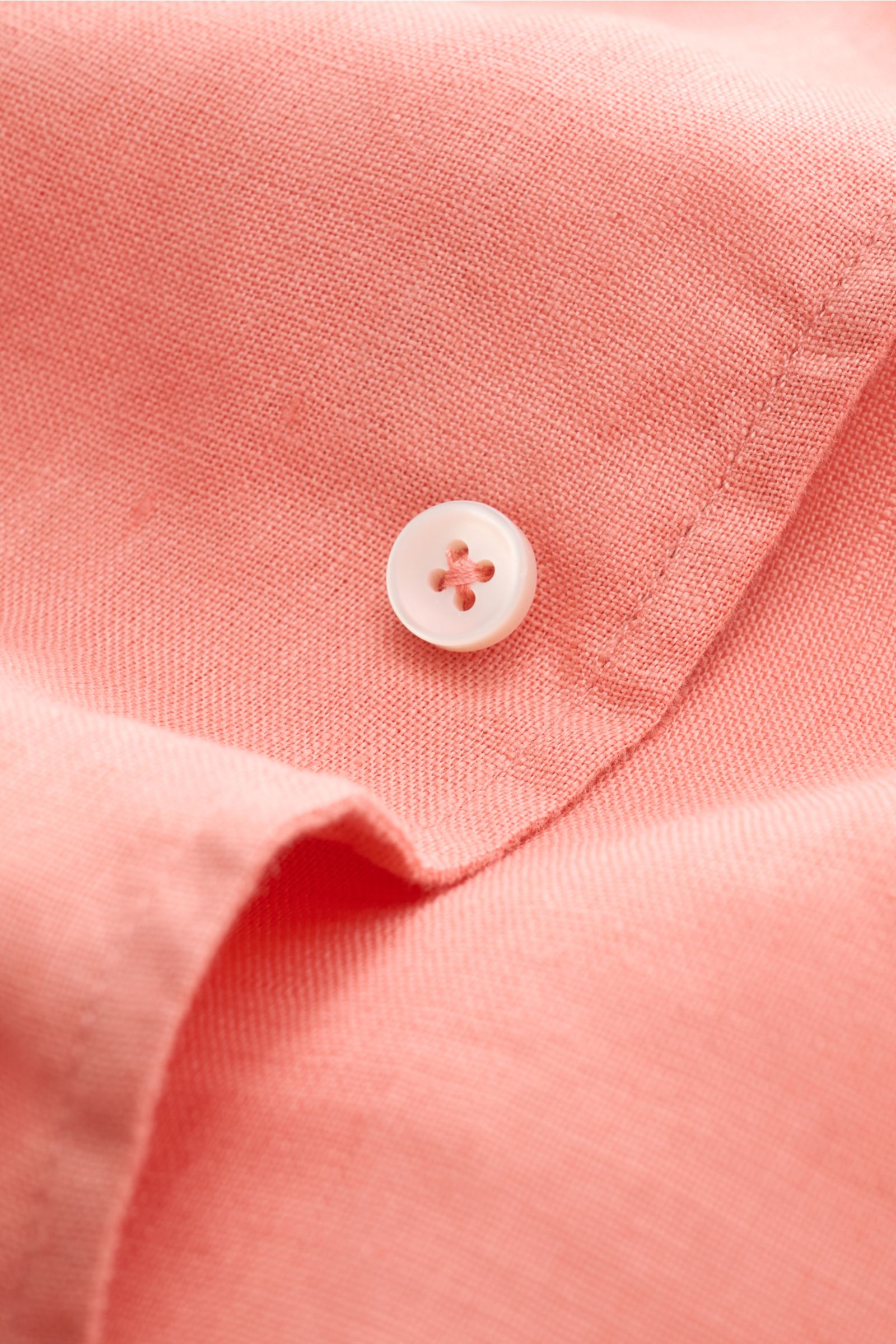 Close-up front view of the Aurélien Linen shirt shark collar coral showing coral-colored pure linen fabric with a white button and detailed stitching.

Want to get into the holiday mood? With its fine linen fabric, this versatile shirt by the brand AUR