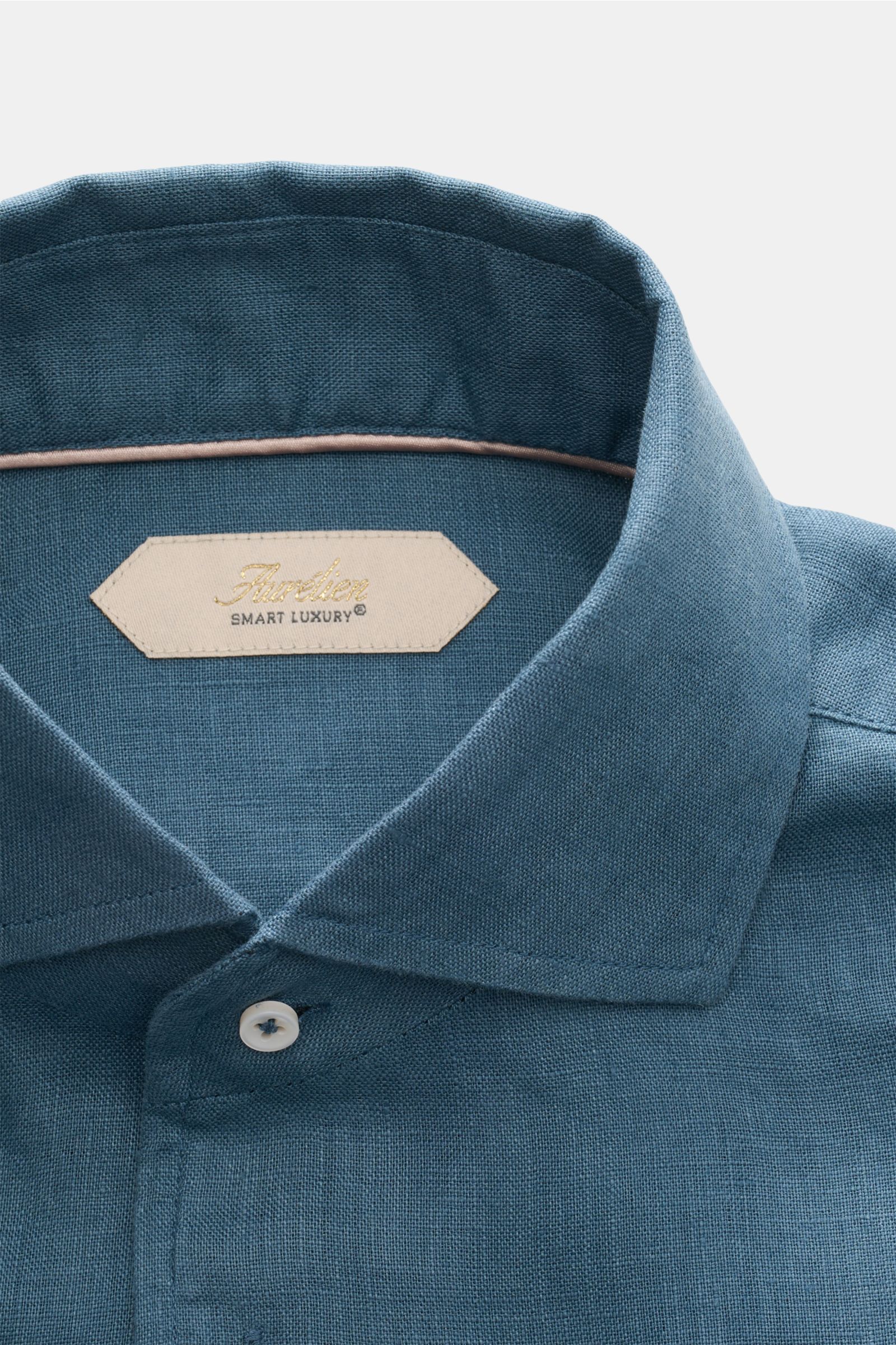 Close-up front view of Aurélien Linen shirt shark collar grey-blue, showcasing fine linen fabric, shark collar, and white button.

Want to get into the holiday mood? With its fine linen fabric, this versatile shirt by the brand AURÉLIEN is an all-round