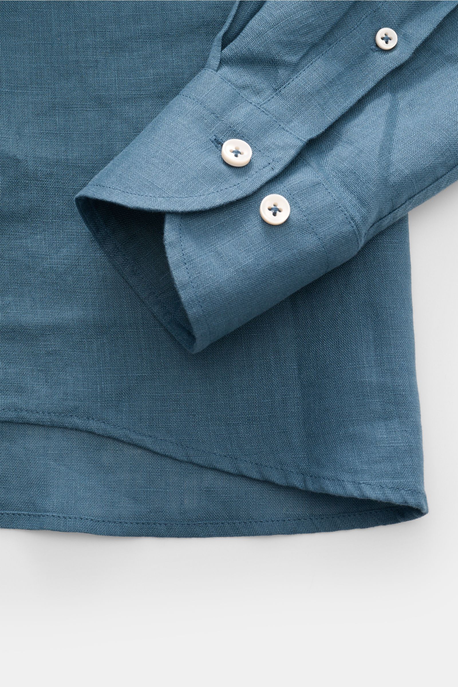 Close-up front view of the sleeve and hem of the Aurélien Linen shirt shark collar grey-blue, showing fine linen texture and white buttons.

Want to get into the holiday mood? With its fine linen fabric, this versatile shirt by the brand AURÉLIEN is an