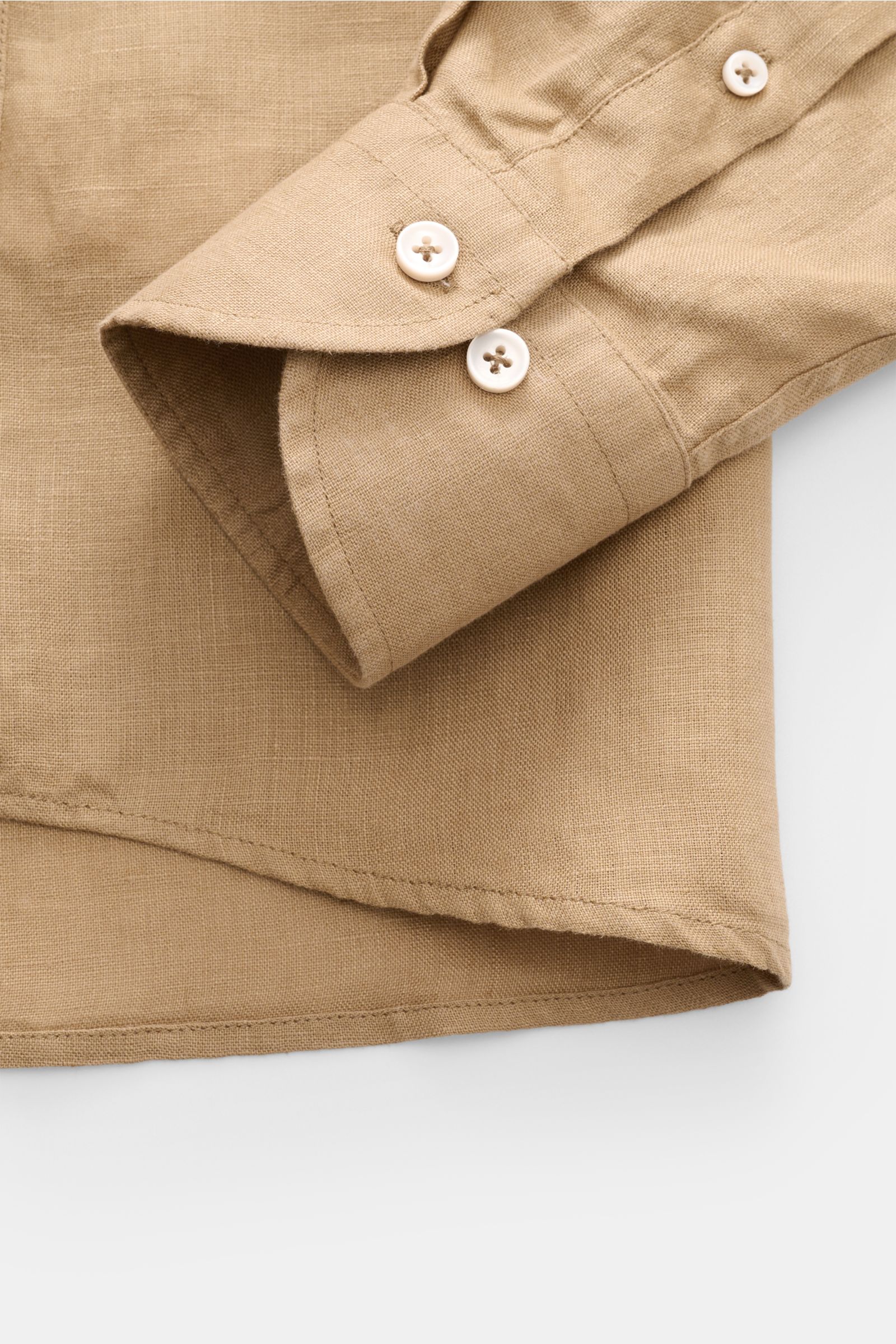 Close-up front view of the Aurélien Leinenhemd Haifisch-Kragen sand, showing soft pure linen fabric, slim fit cuff with two buttons, rounded hem.

Description: Ein wenig Urlaubsfeeling gefällig? Das vielseitig einsetzbare Hemd der Marke AURÉLIEN wird m
