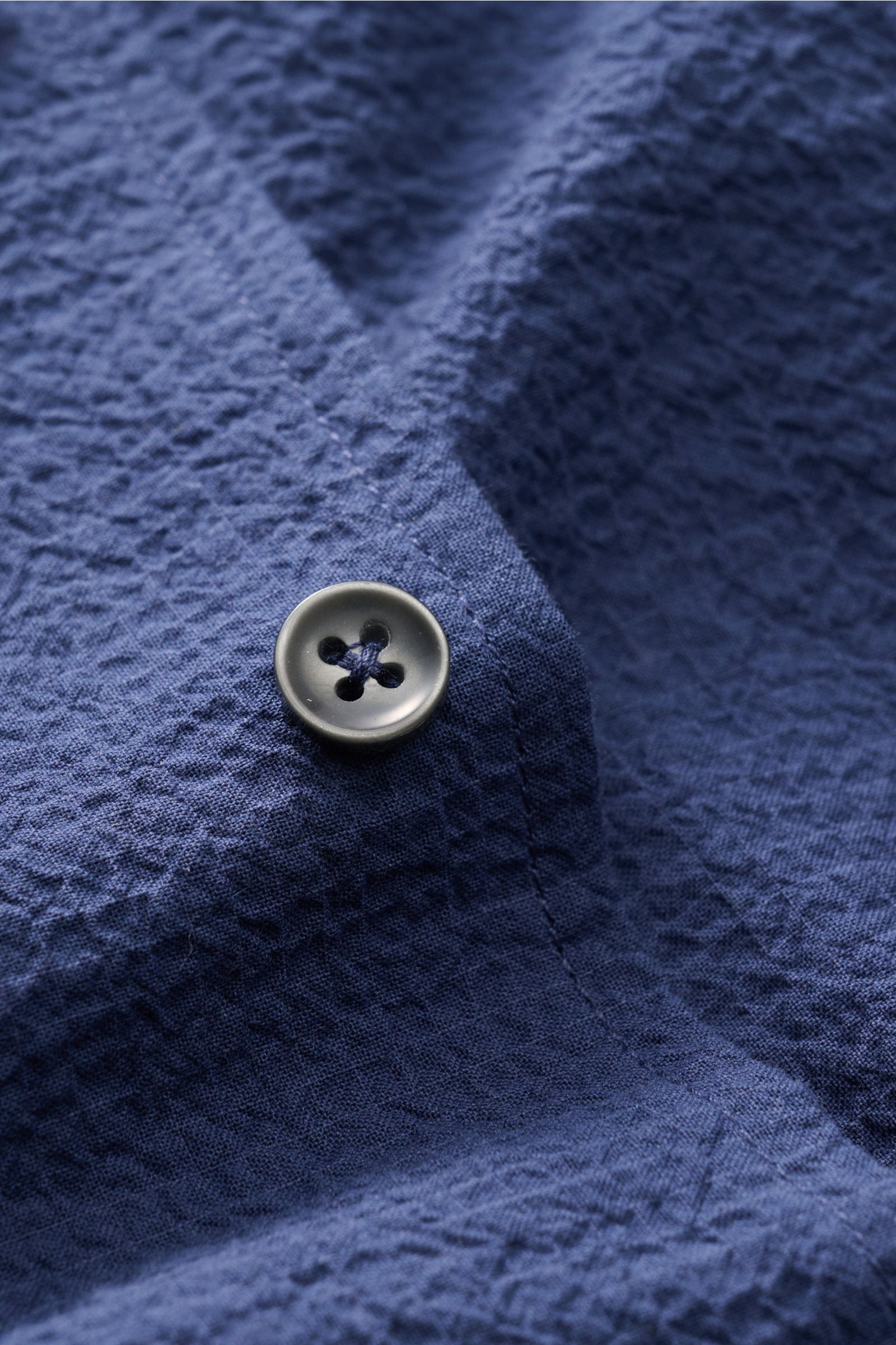 Close-up of Aurélien Seersucker-Hemd Haifisch-Kragen dunkelblau fabric and button, showing textured cotton seersucker material from a top-down perspective.

Sommerlicher Eyecatcher: Das Hemd von AURÉLIEN überzeugt mit charakteristischem Seersucker-Desi
