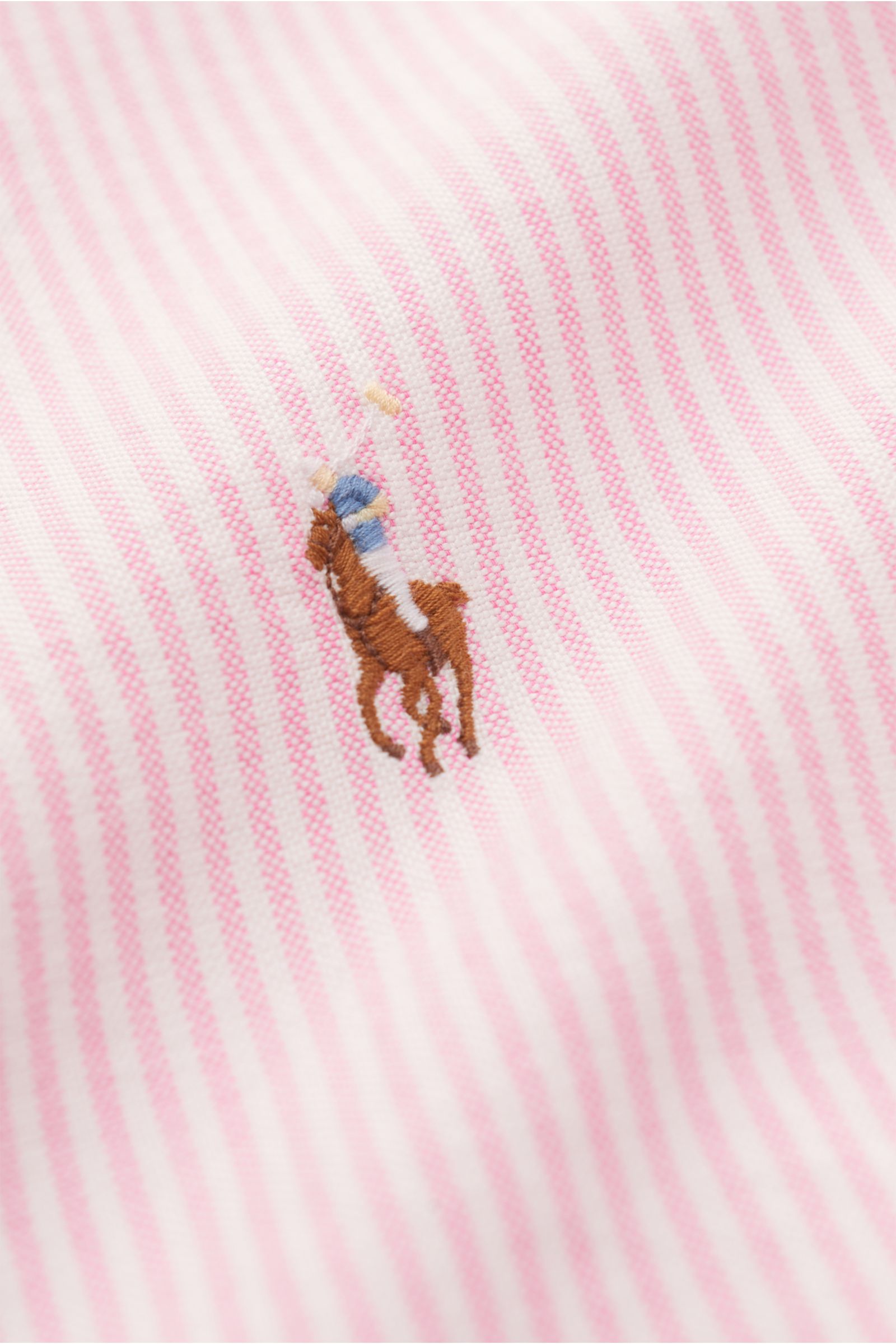 Close-up front view of the Polo Ralph Lauren Oxfordhemd Button-Down-Kragen rosé/weiß gestreift showing soft cotton fabric with pink and white stripes and embroidered logo.

Zeitloser Allrounder: Das Oxford-Hemd von POLO RALPH LAUREN verbindet klassisch