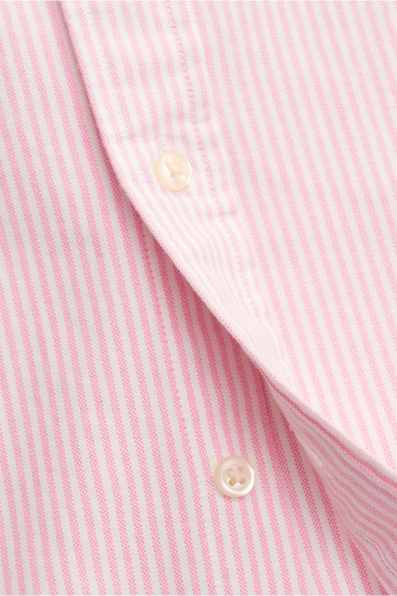 Close-up front view of Polo Ralph Lauren Oxfordhemd Button-Down-Kragen rosé/weiß gestreift with fine pink and white stripes and buttons.

Zeitloser Allrounder: Das Oxford-Hemd von POLO RALPH LAUREN verbindet klassisches Streifenmuster mit einer klaren,
