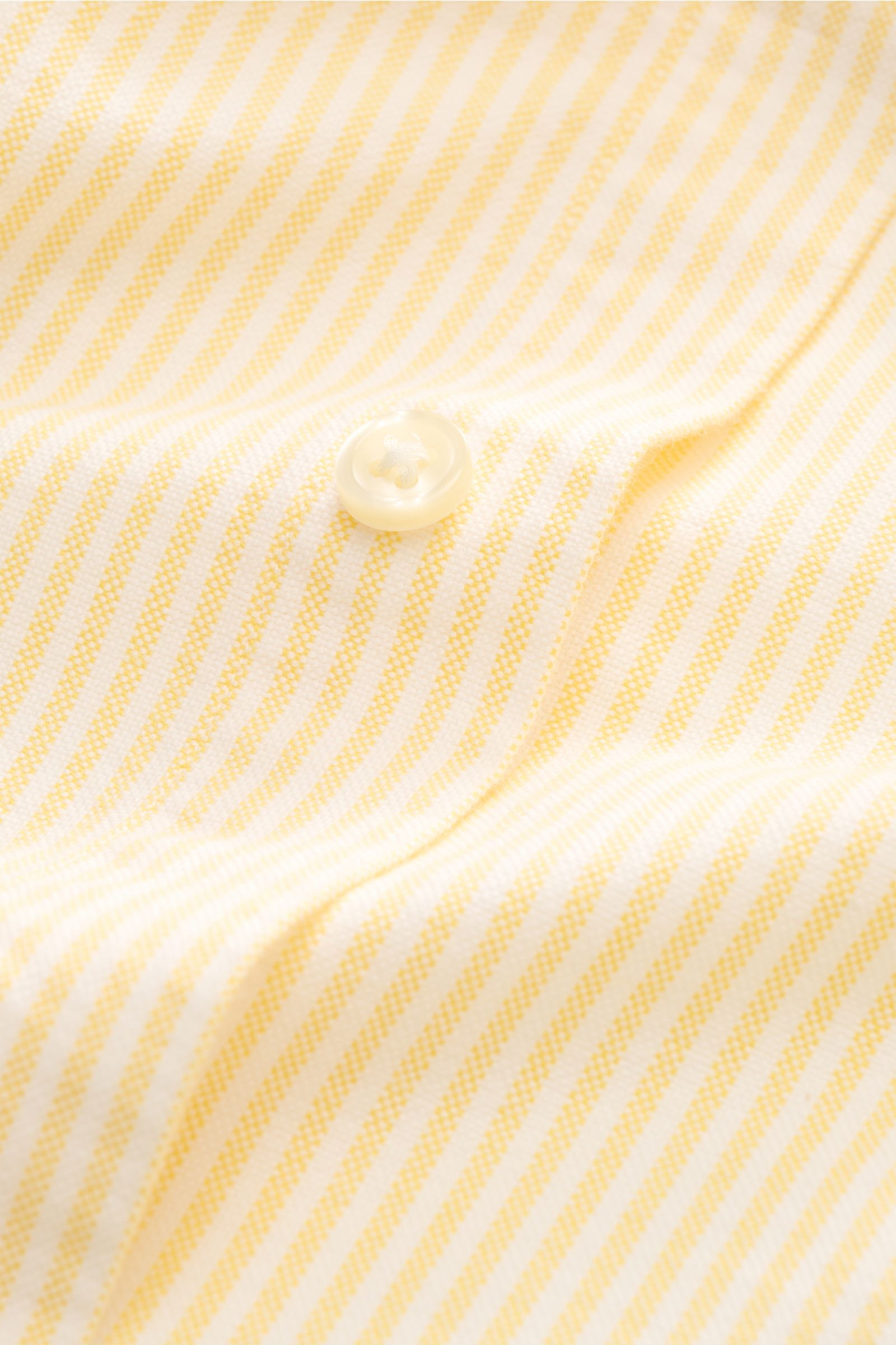 Close-up front view of the Polo Ralph Lauren Oxford-Hemd Button-Down-Kragen gelb/weiß gestreift showing yellow and white stripes and a pearly button, highlighting its fine cotton oxford fabric texture.

Stilvoller Klassiker mit Liebe zum Detail: Dieses