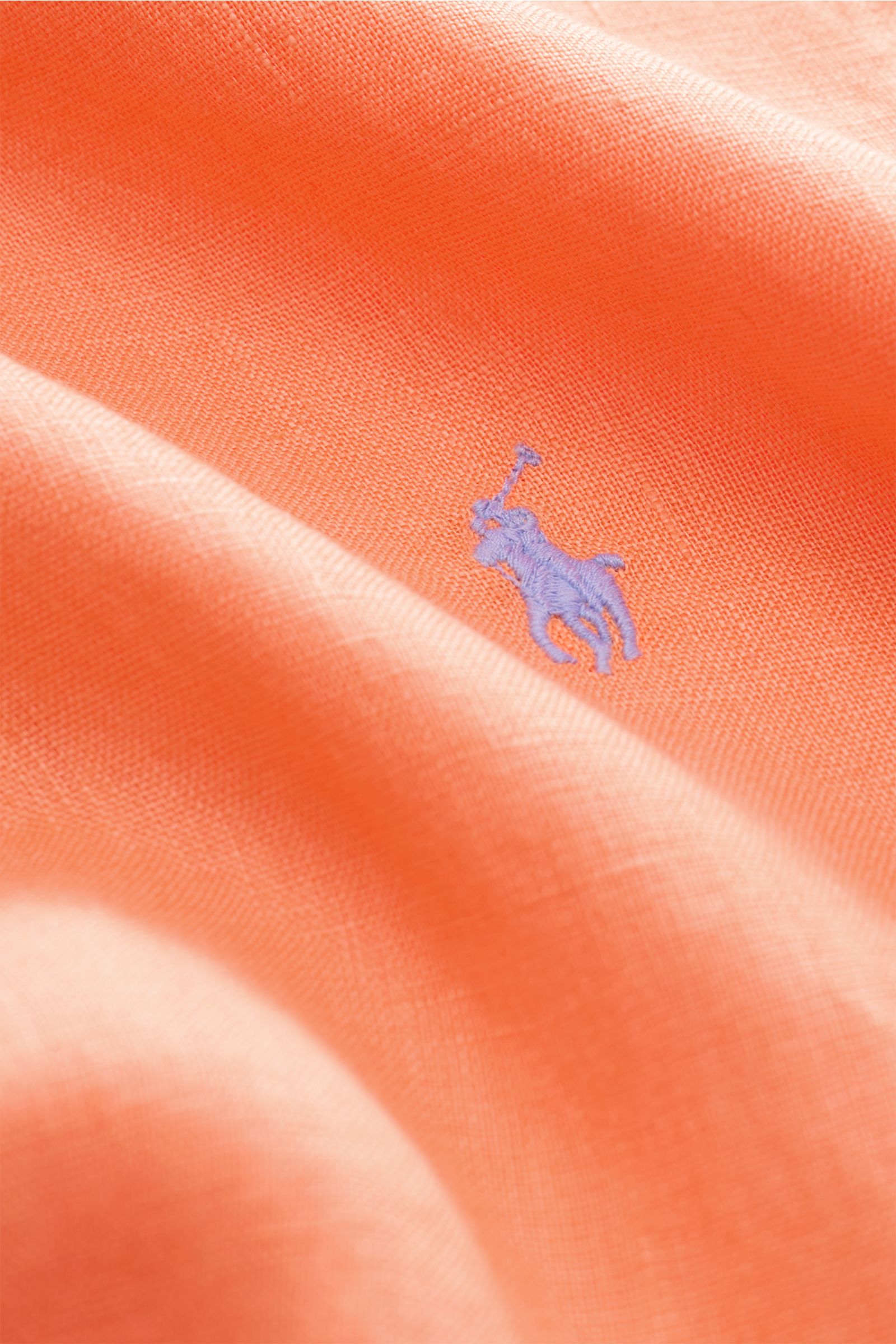 Close-up view of the orange Polo Ralph Lauren Leinenhemd Button-Down-Kragen fabric showing the fine linen texture and purple embroidered logo, highlighting its lightweight, airy quality. Dieses Leinenhemd von POLO RALPH LAUREN ist eine Bereicherung für