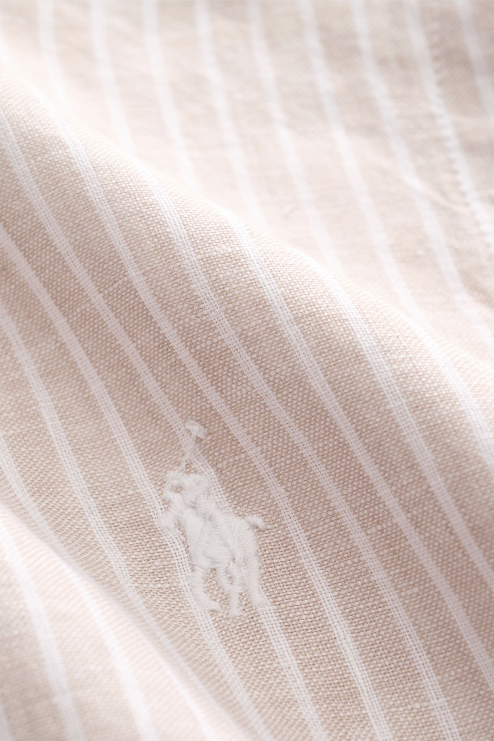 Close-up front view of Polo Ralph Lauren Linen shirt button-down collar beige/white striped, showing fine linen texture and signature logo stitching. A summer classic from POLO RALPH LAUREN: This minimalist slim fit shirt in the finest linen with button-d
